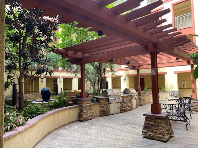 Courtyard - two lidded barbecues with stone shelves and  moveable patio furniture; shady trees and an arbor