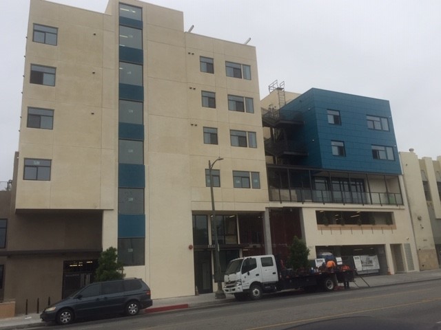 Front view of pico robertson. Multi-story tan building with accents of blue