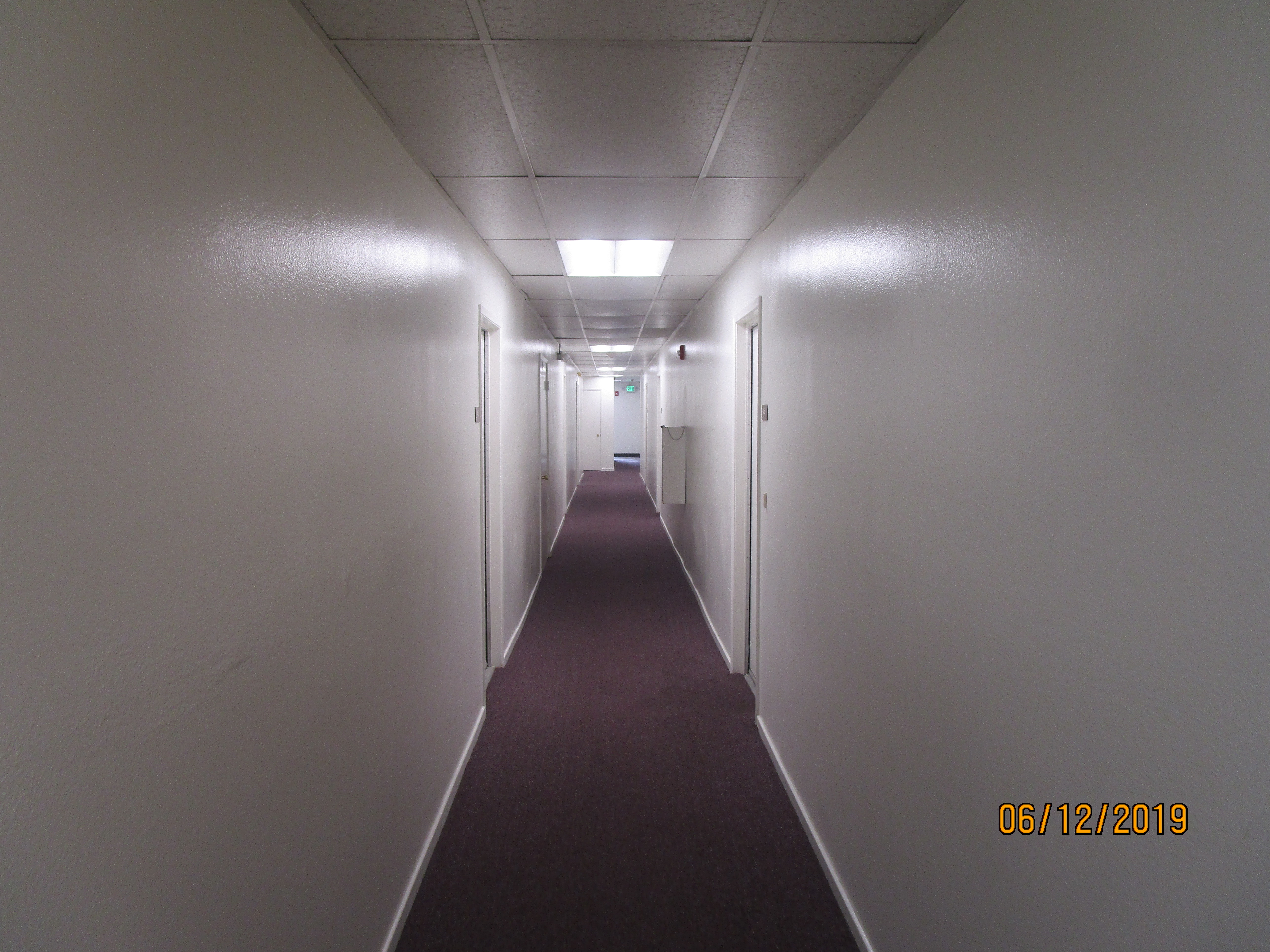 Front view of a carpeted hallway, white walls.