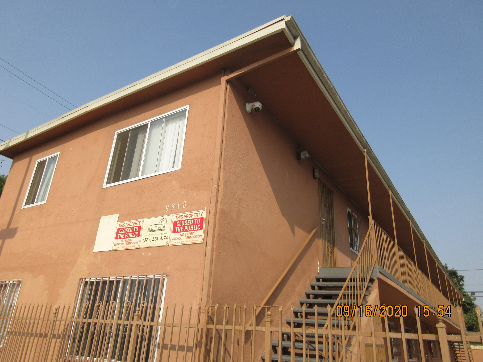 Corner view of a two story building, building number and management signs on the wall.