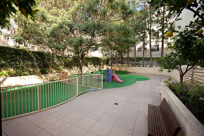 Exterior view of the outside building common area showing a colorful slide and bushes.