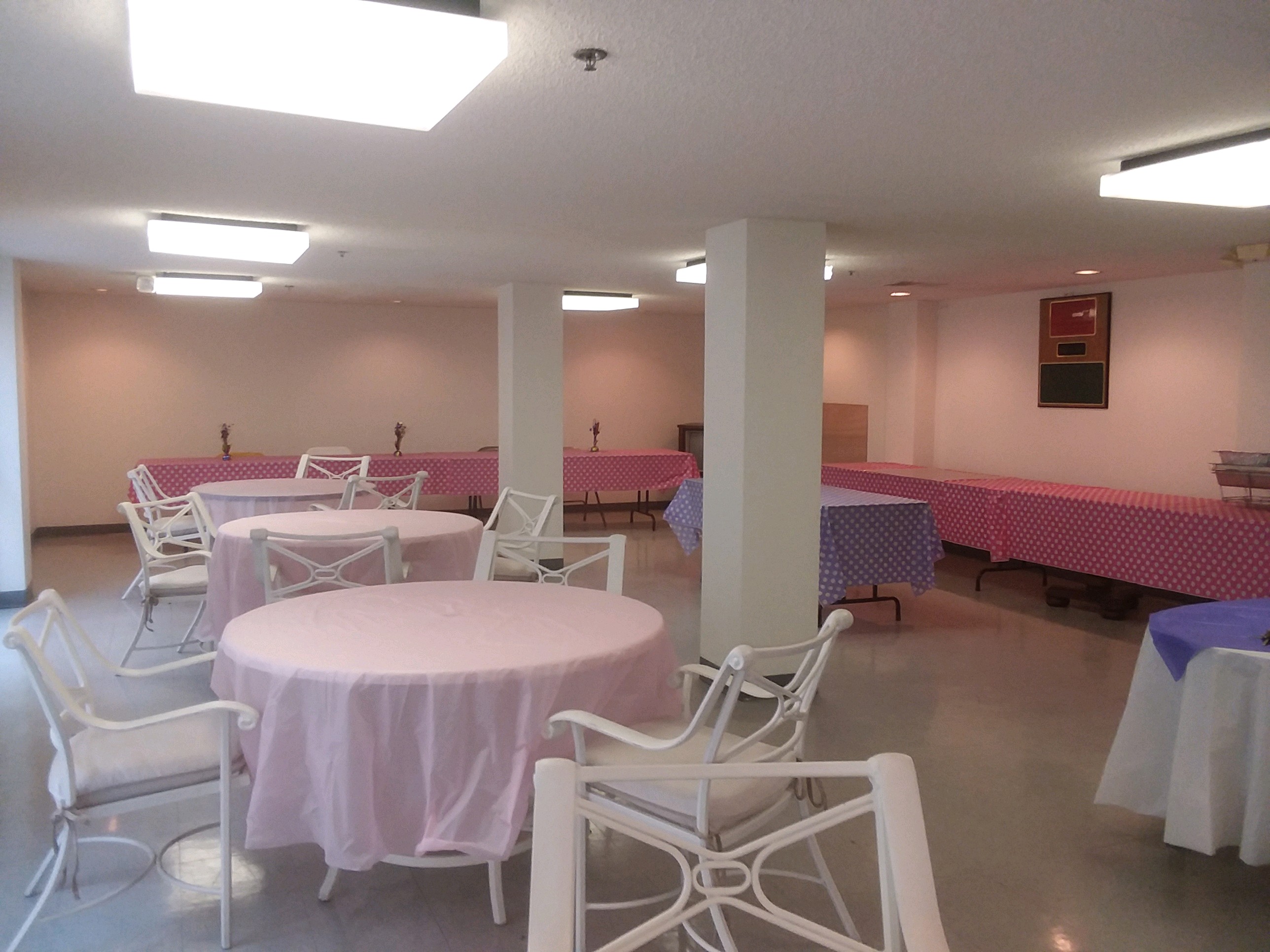 Interior view of a community room at Fame Manor. Round tables and chairs with retangular tables along the walls