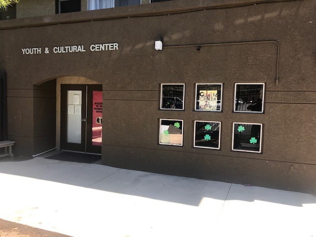 Side view of the main entrance to a Youth and Cultural Center, brown walls, double side brown and glass doors.