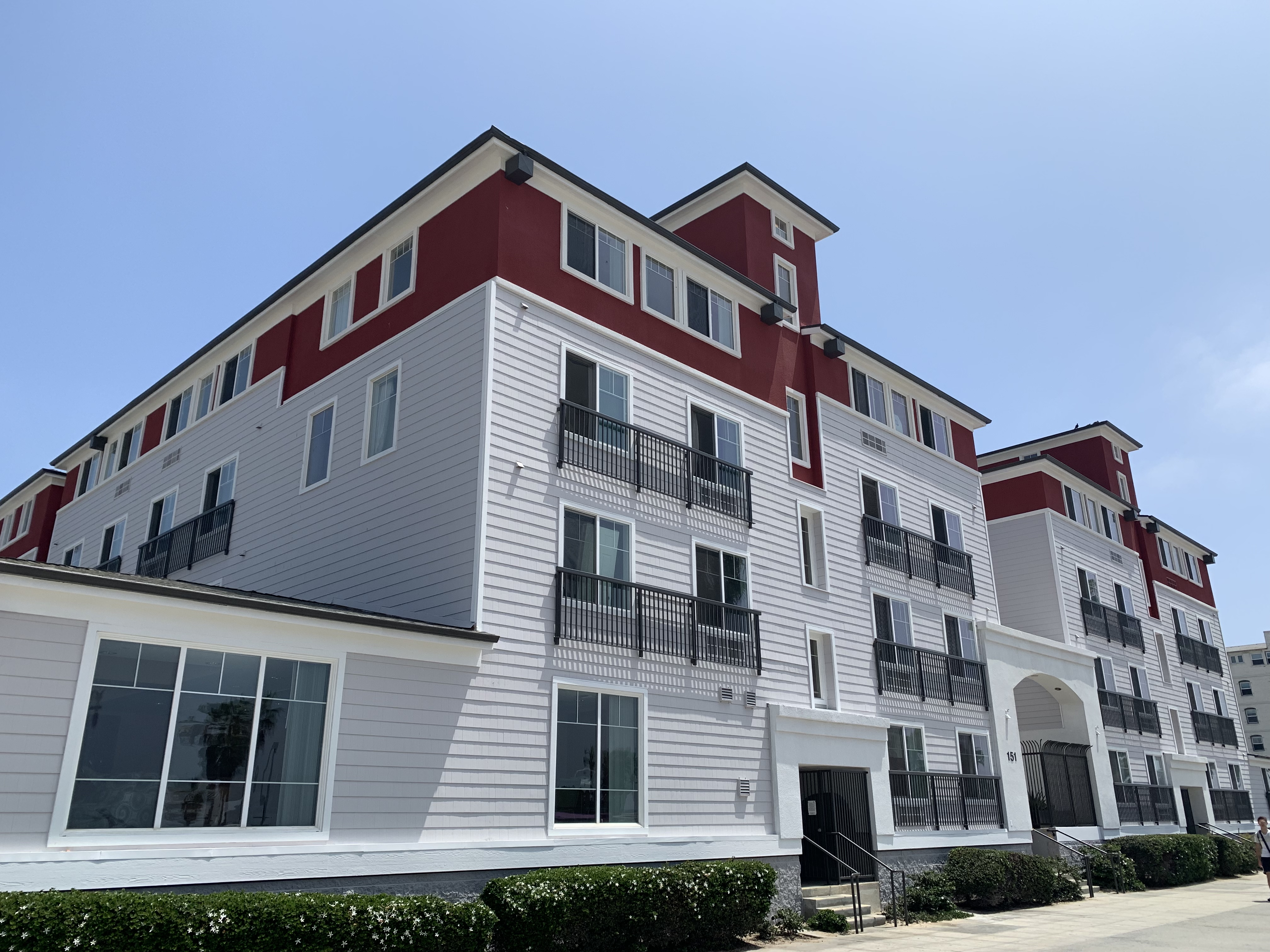 Image of 4 floor building with stairs to entrance and hedges along building