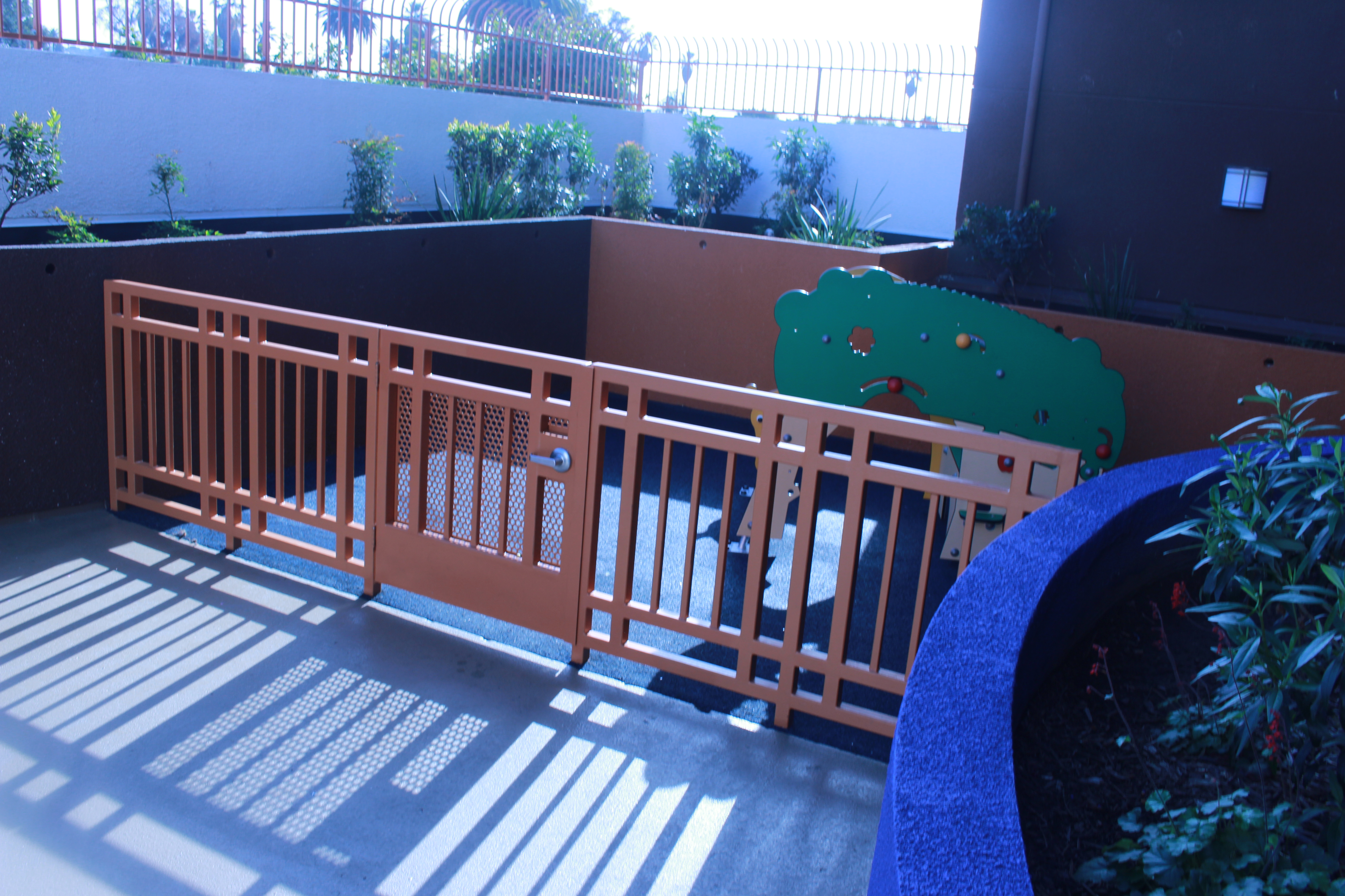 Playground with a brown iron gate, plants around.