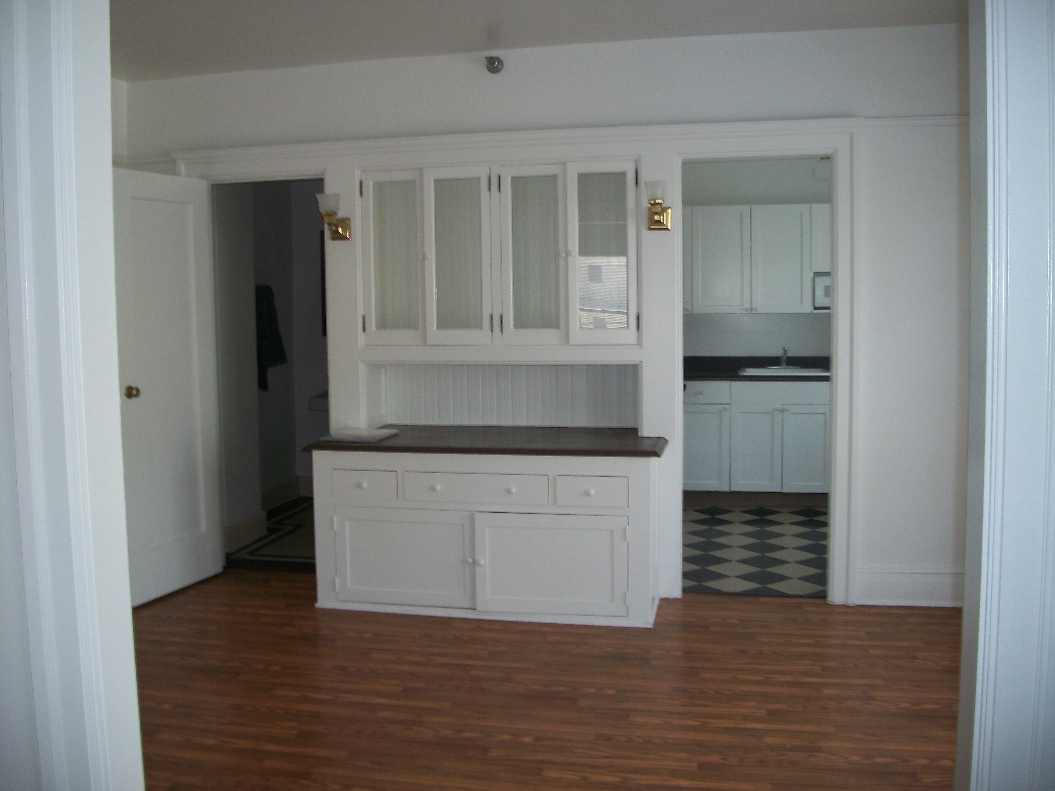 Interio view of a unit at the Younge Apartments. White walls with patterned floor tile in the kitchen. A built in hutch with dark counter space.