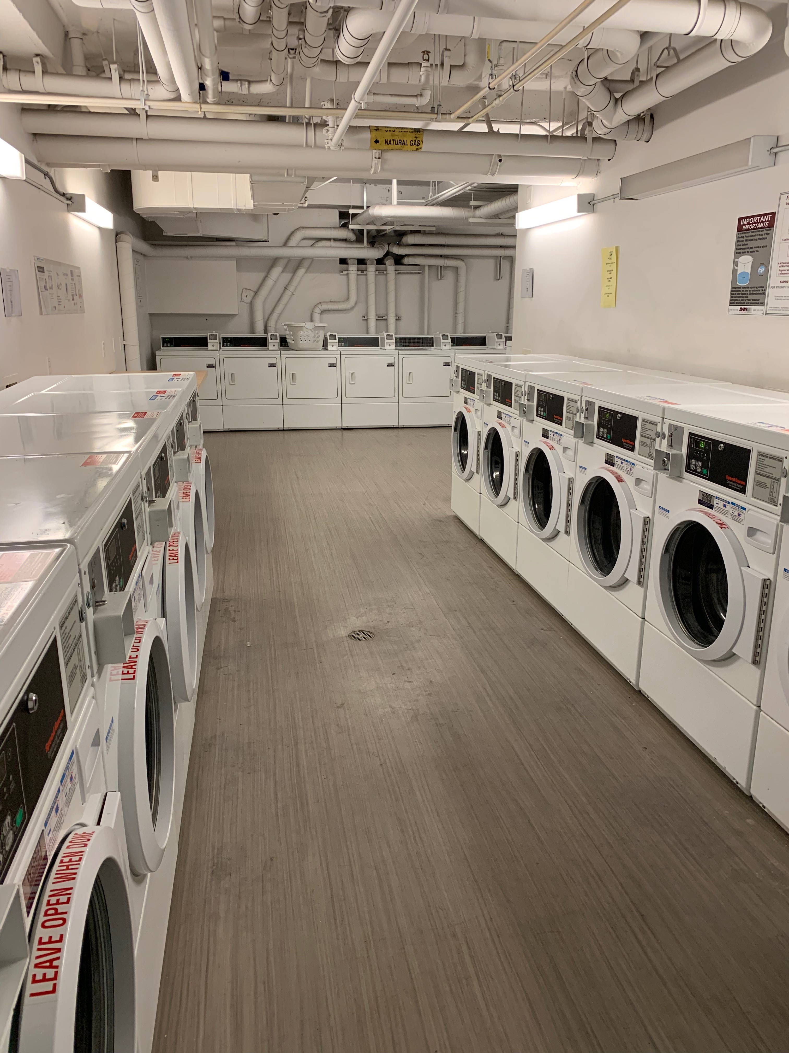 Laundry room with several washer and dryer appliances set up in an L shaped passageway.