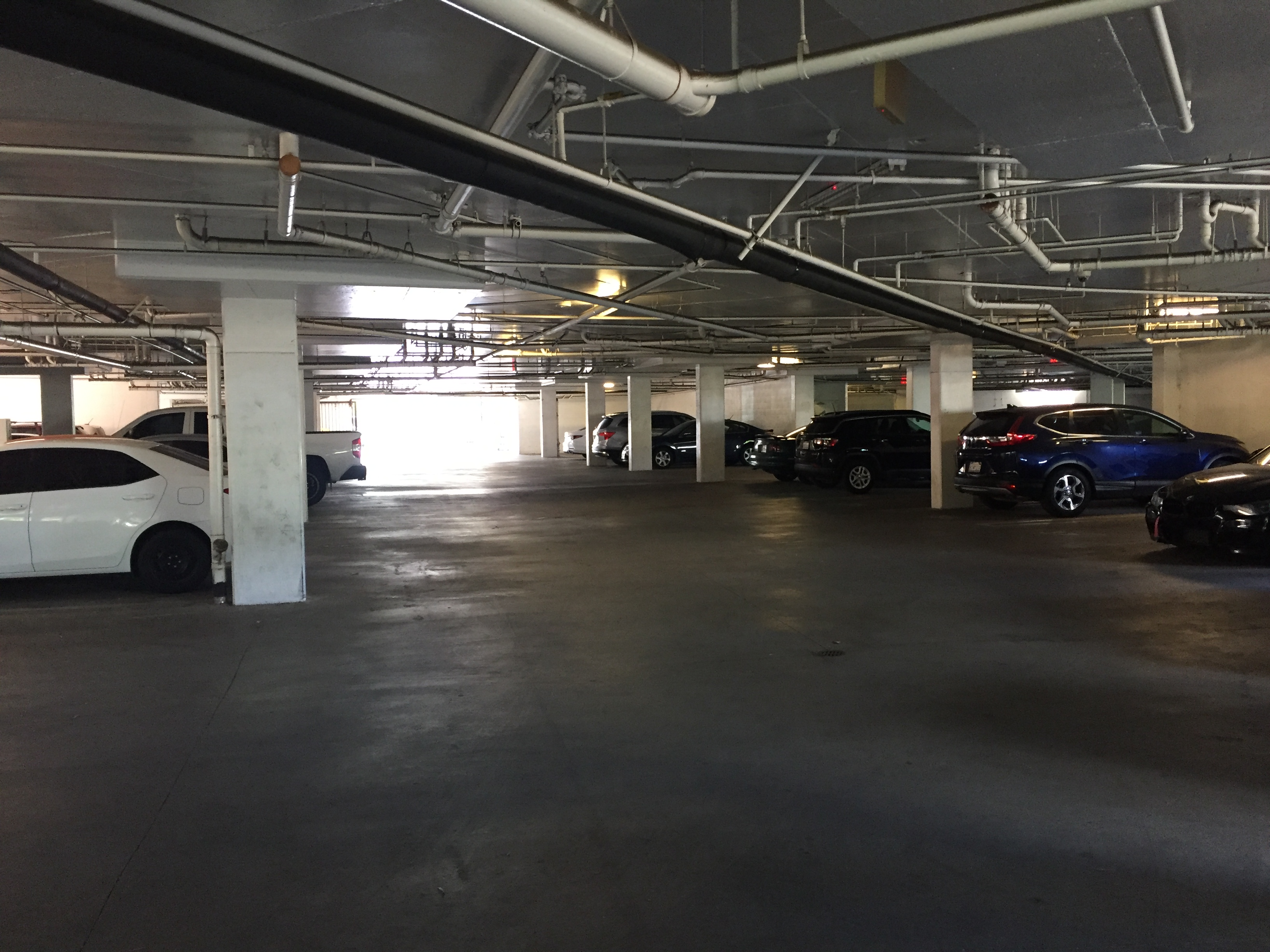 View of a covered parking lot. There are piped on the ceiling.