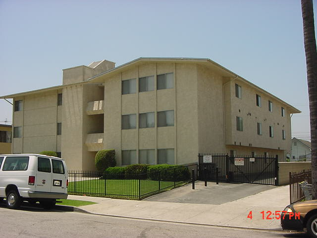 Street view of three story gated building. Gated parking area along side building. Walkway to building entrance with well kept yard