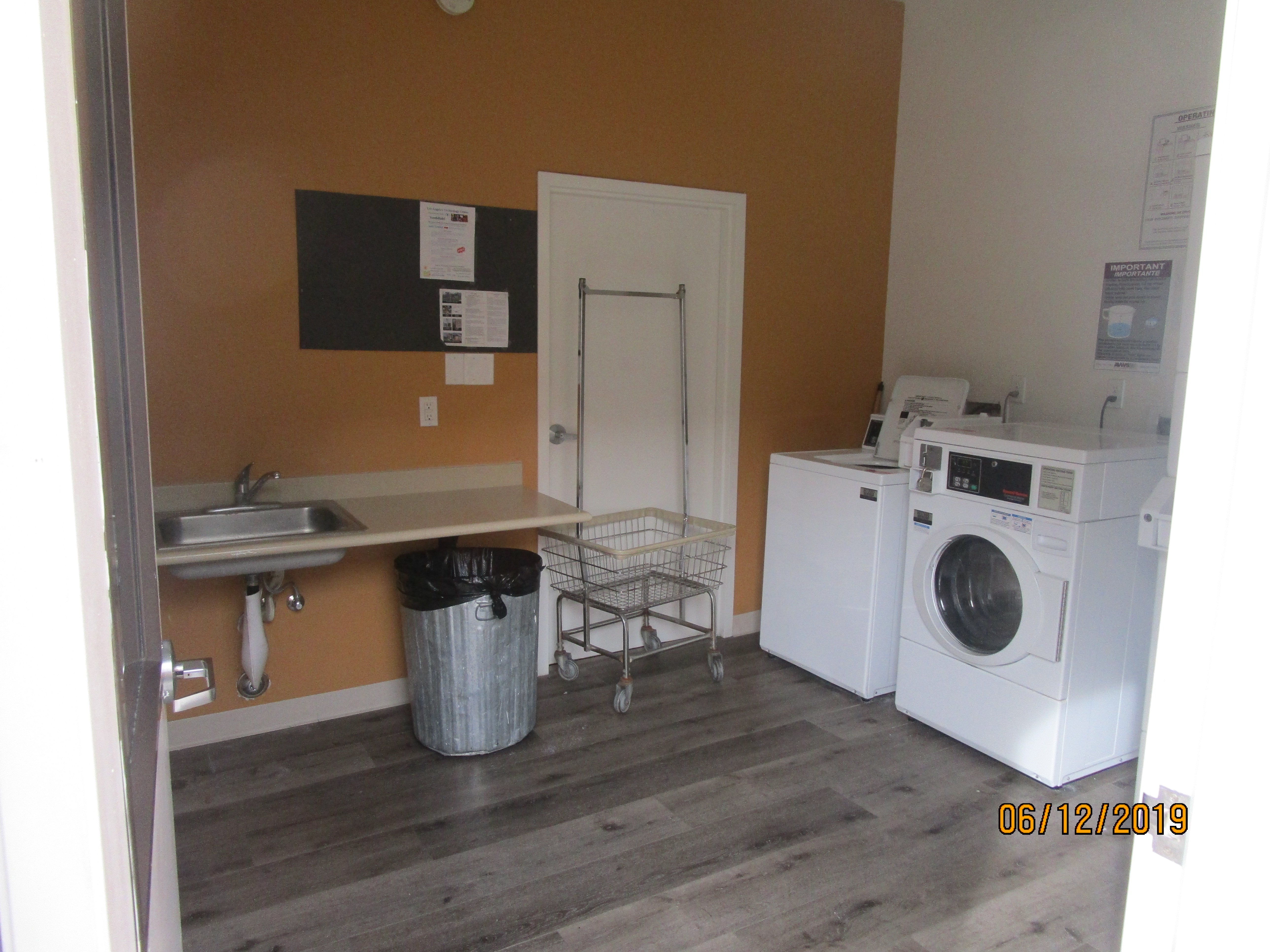 Image of the building laundry room equipped with a machine, trash can and notice board