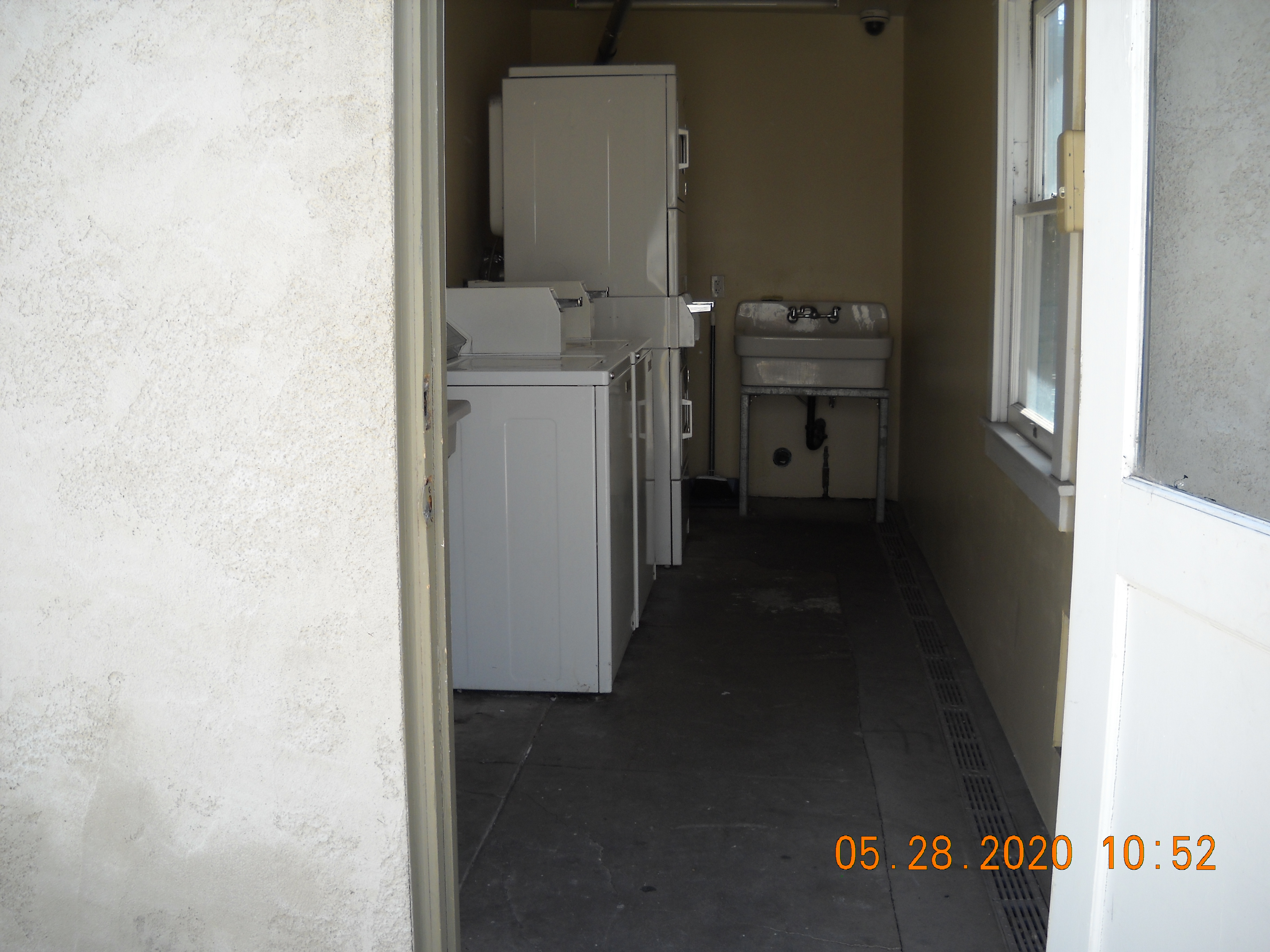 View of a laundry room with two washer and two dryers. There is a sink and a window.