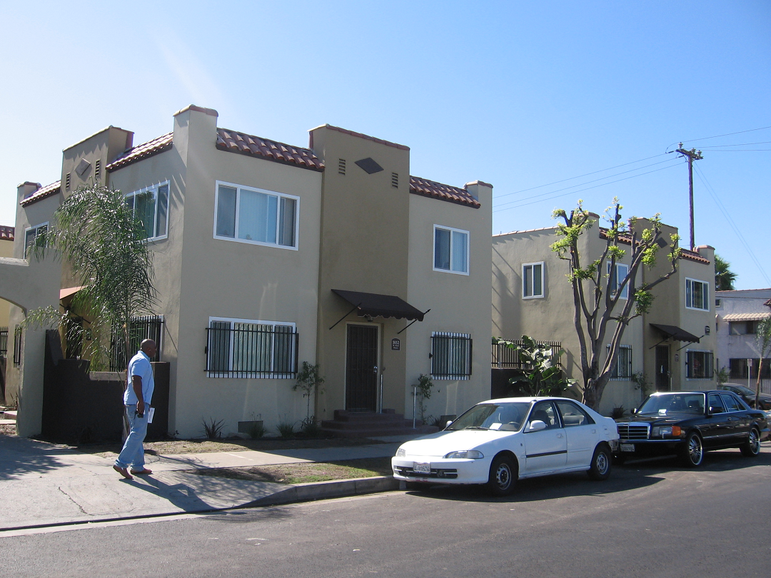 Street view of one story residential complex divided into two buildings. Property color is light green and have parking on premises