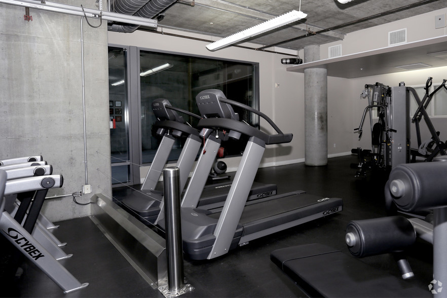 View of a fitness room with treadmills, a leg press machine and weight stack machine.