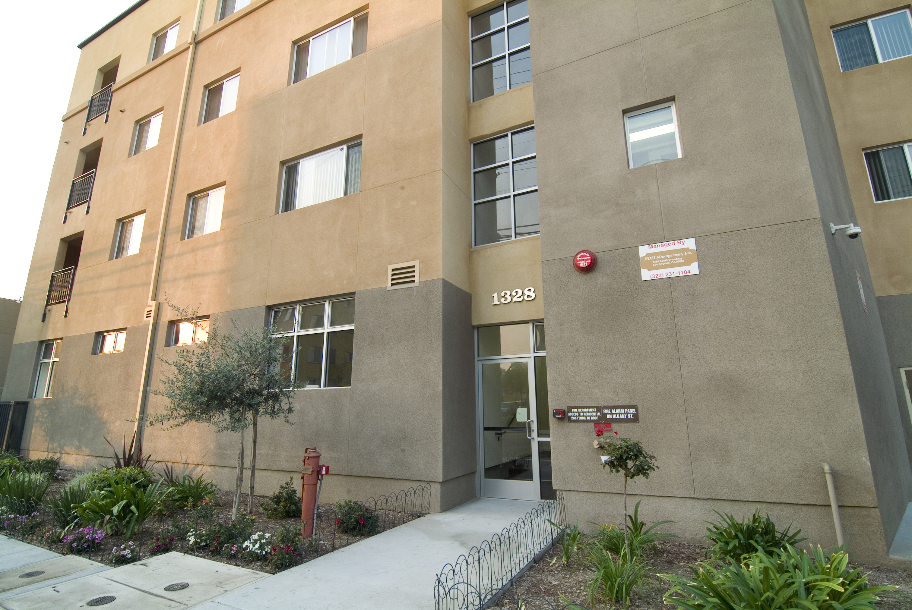 Exterior view of the side entrance to James Wood Apartments, 4 story brown building with landscaping