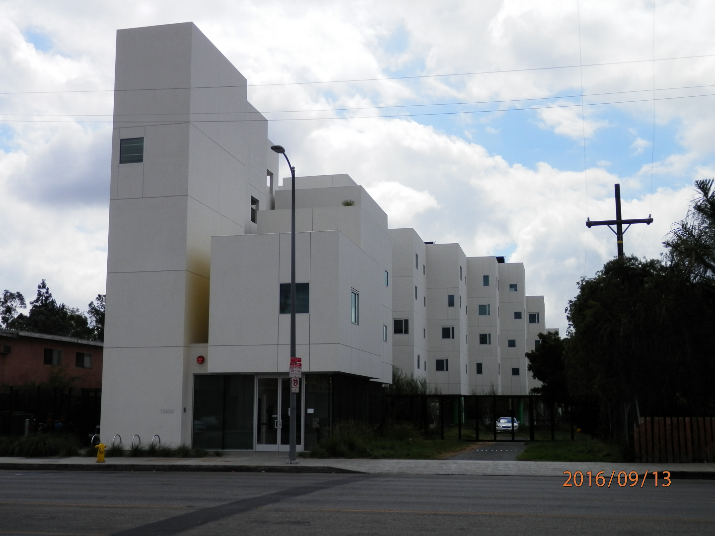 Street view of four story building with parking on premises and front entrance,
