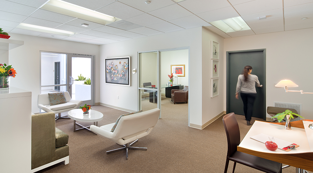 Interior view of Agyle Apartments. An interior view of an office space with white walls, white modern couches in waiting area and brown guest chairs in the office rooms.