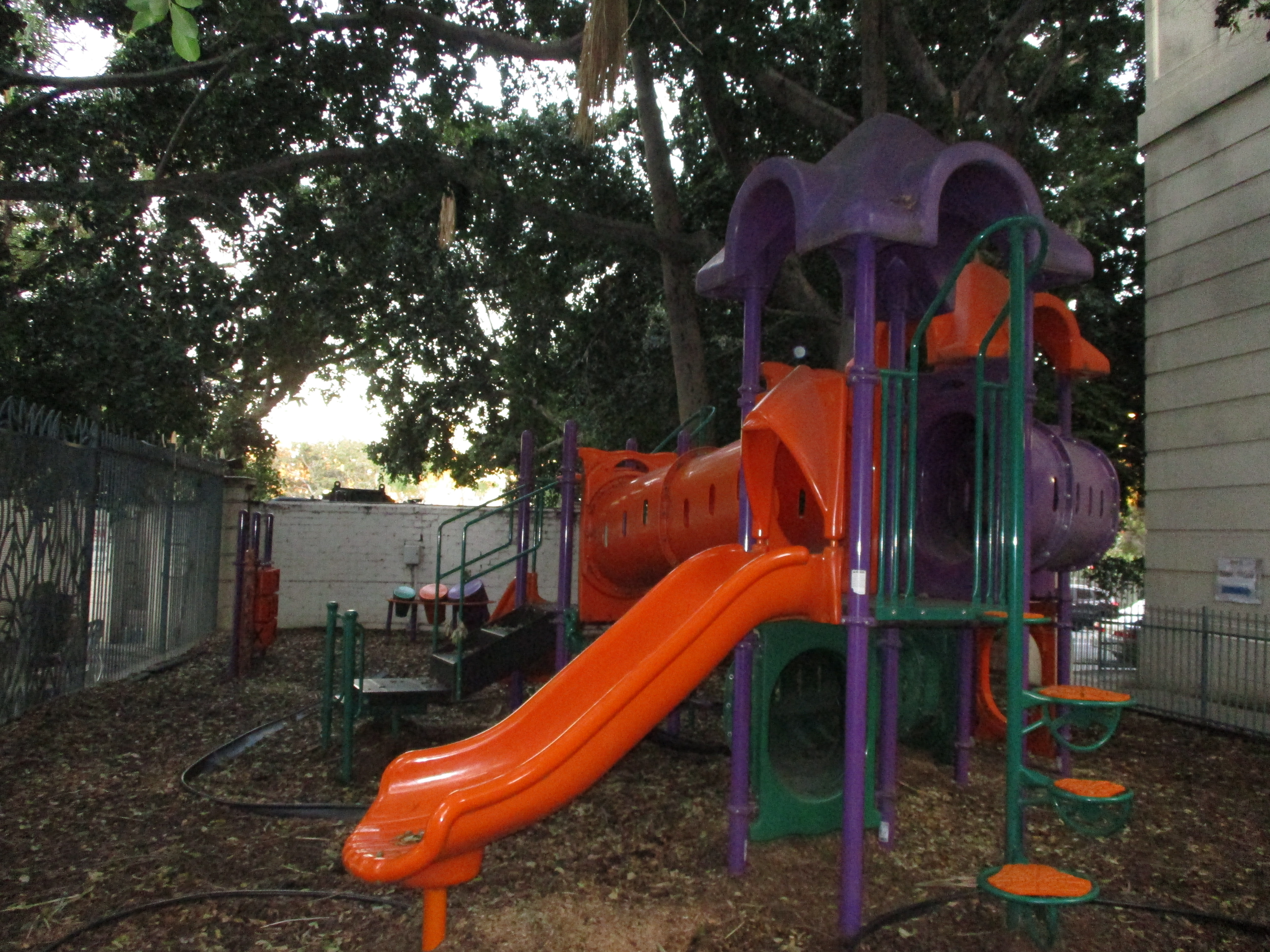Image of Sheraton town house playground. Large jungle gym shaded by large tree