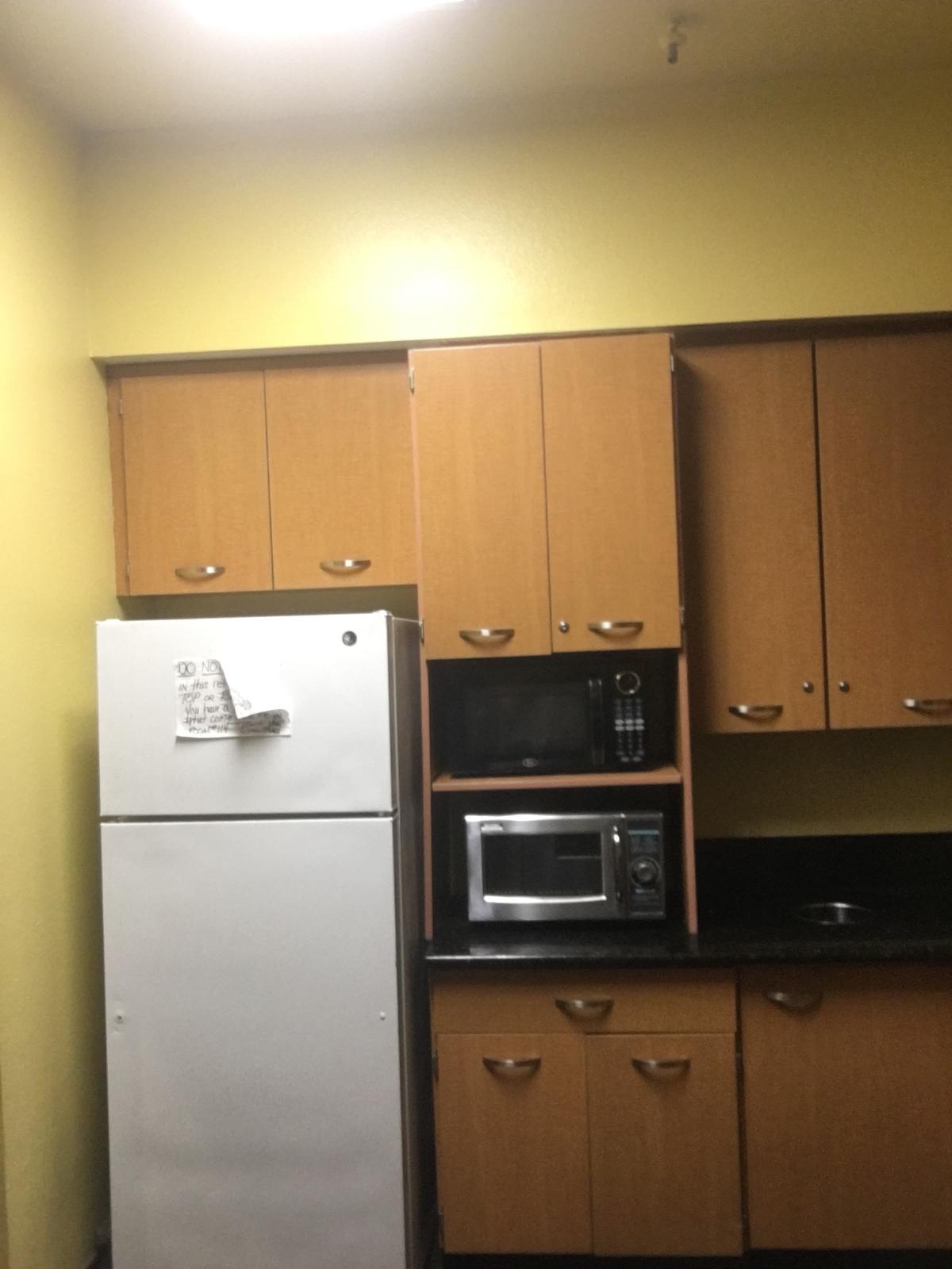 Photo of Kitchen area with kitchen cabinets, sink and two microwave ovens.