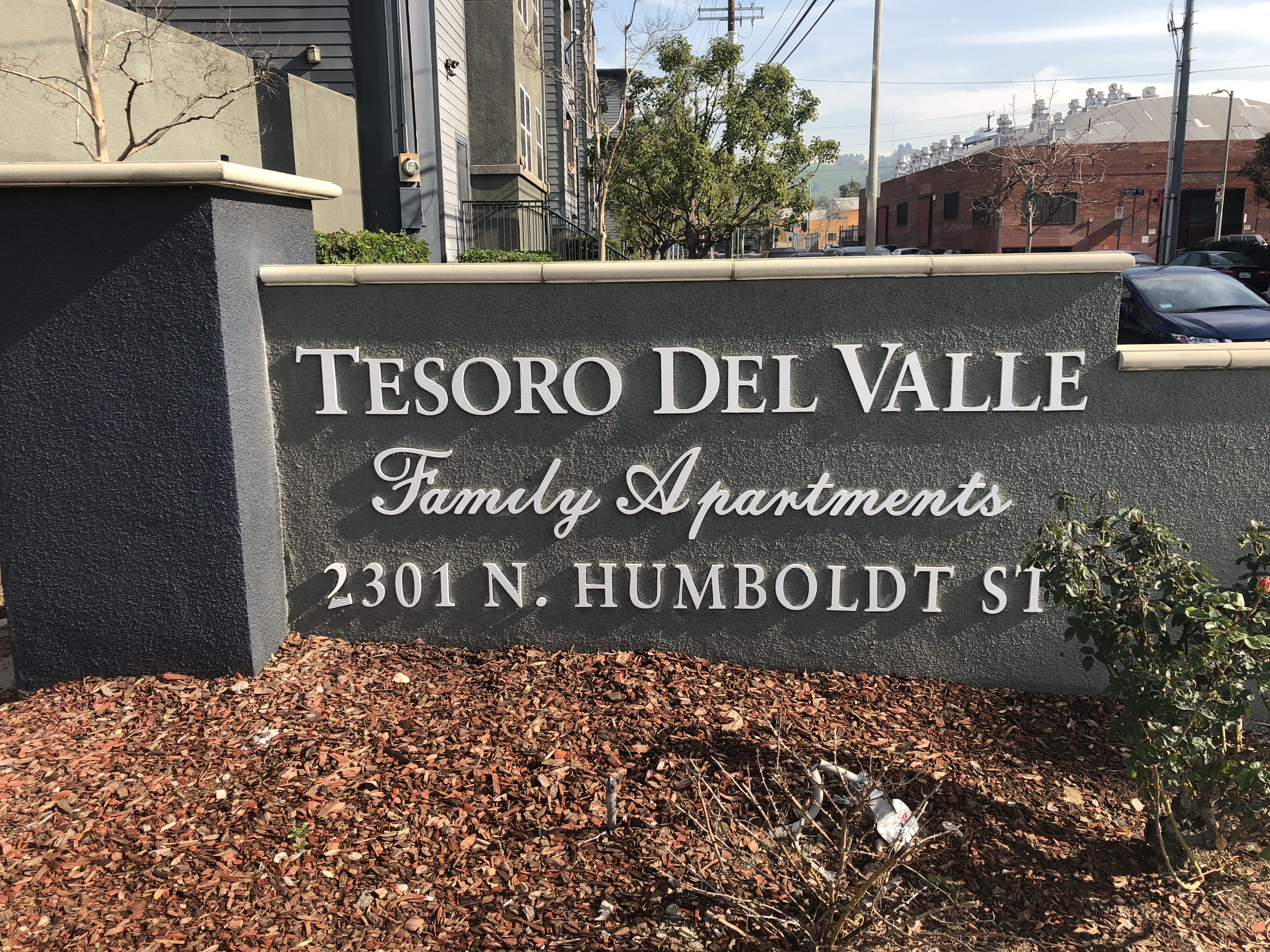 Monument-style wall displaying the name of the property: "Tesoro Del Valle Family Apartments, 2301 N. Humboldt St."
