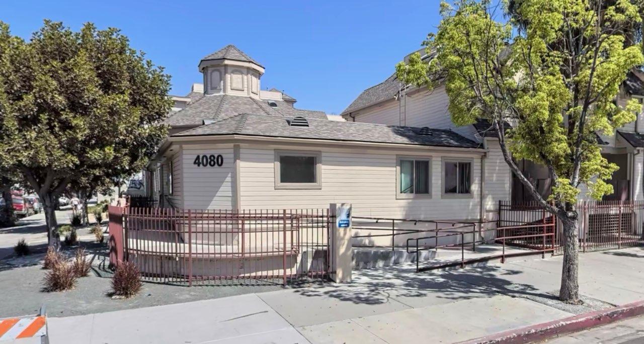 Photo of the apartment, with a fence, on ramp access and trees.