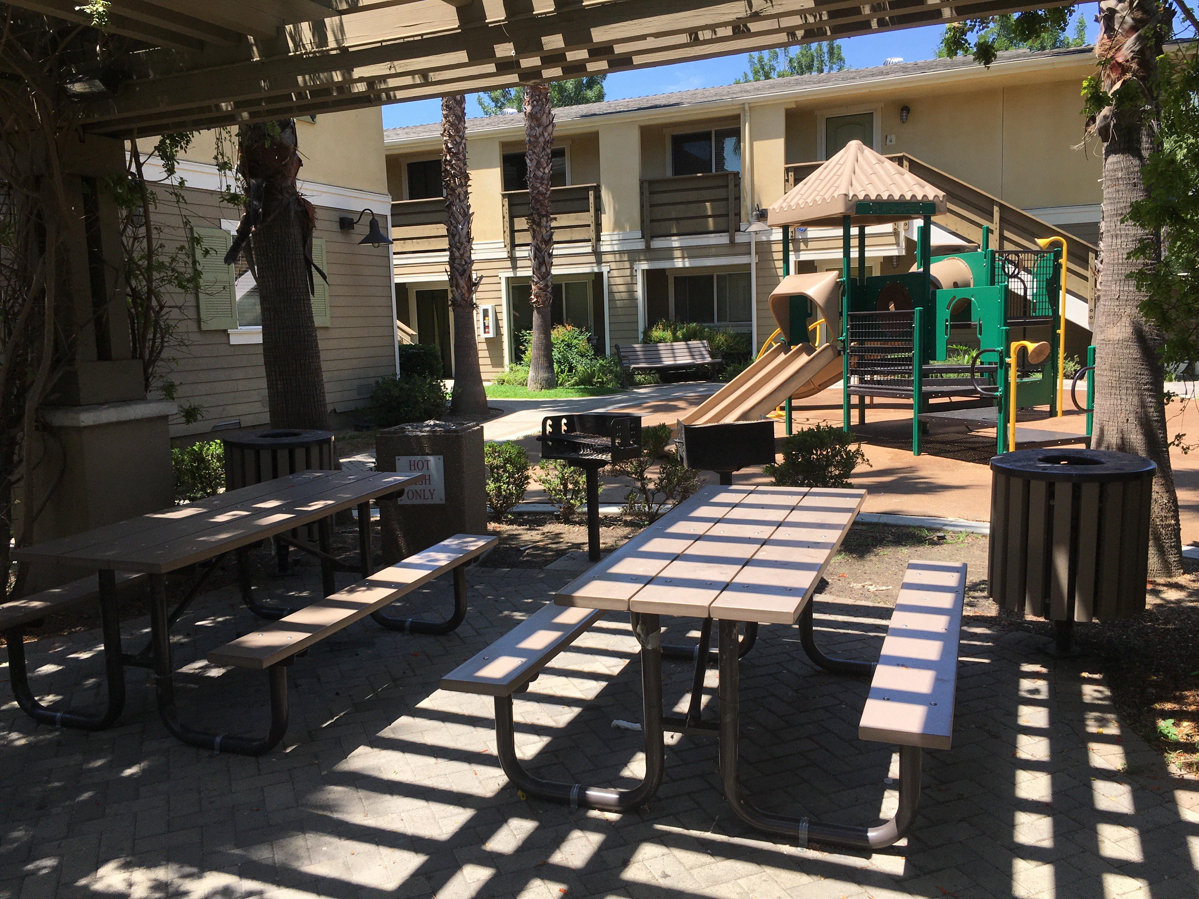 View of a Bar BQ area, two picnic tables with benches, playground.