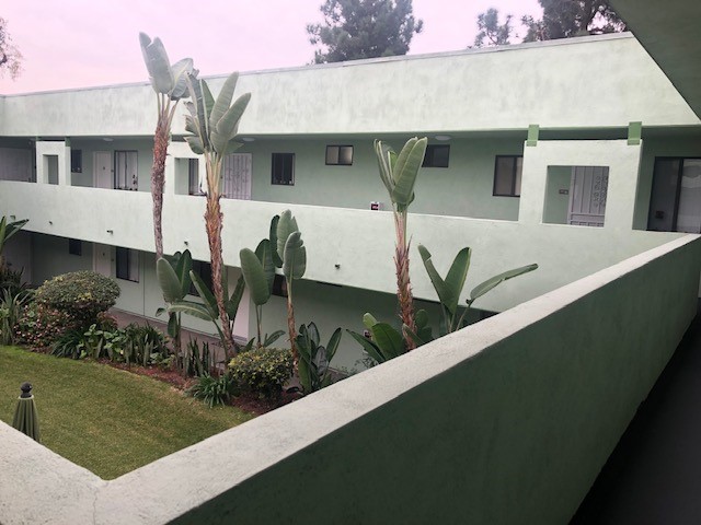 Side view of a courtyard patio from second floor, grass, bushes and trees.