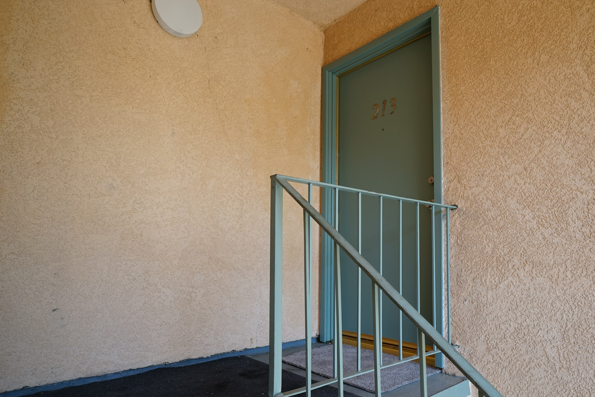 View of a unit's door that has a railing on the side.