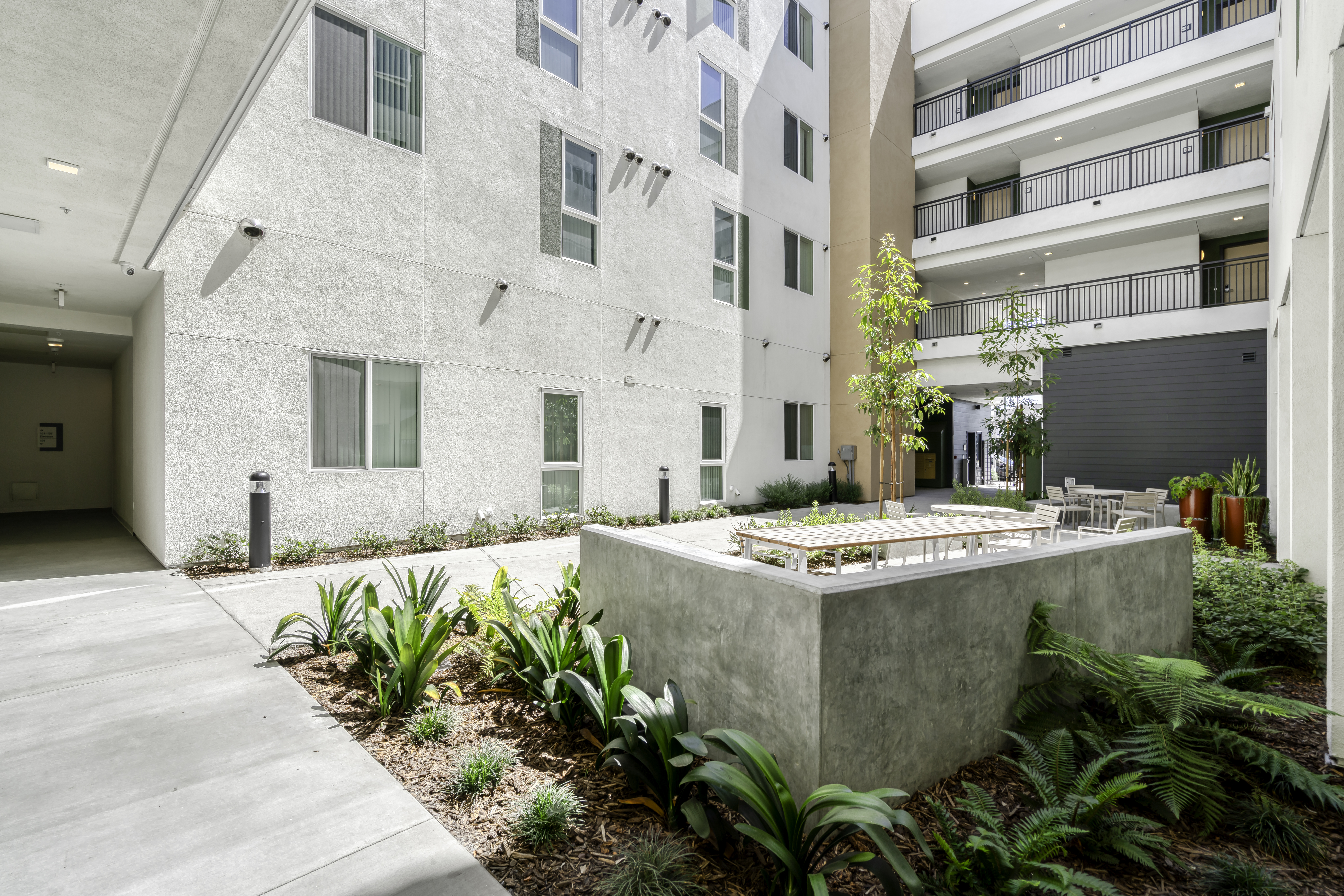 Common Area. Picture from courtyard showing three floors of units, the seating area, and the entrance/exit gate.