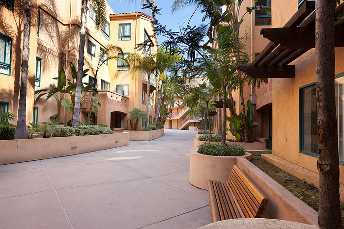 Exterior view of a walkway with a bench to one side between buildings at La Villa Mariposa