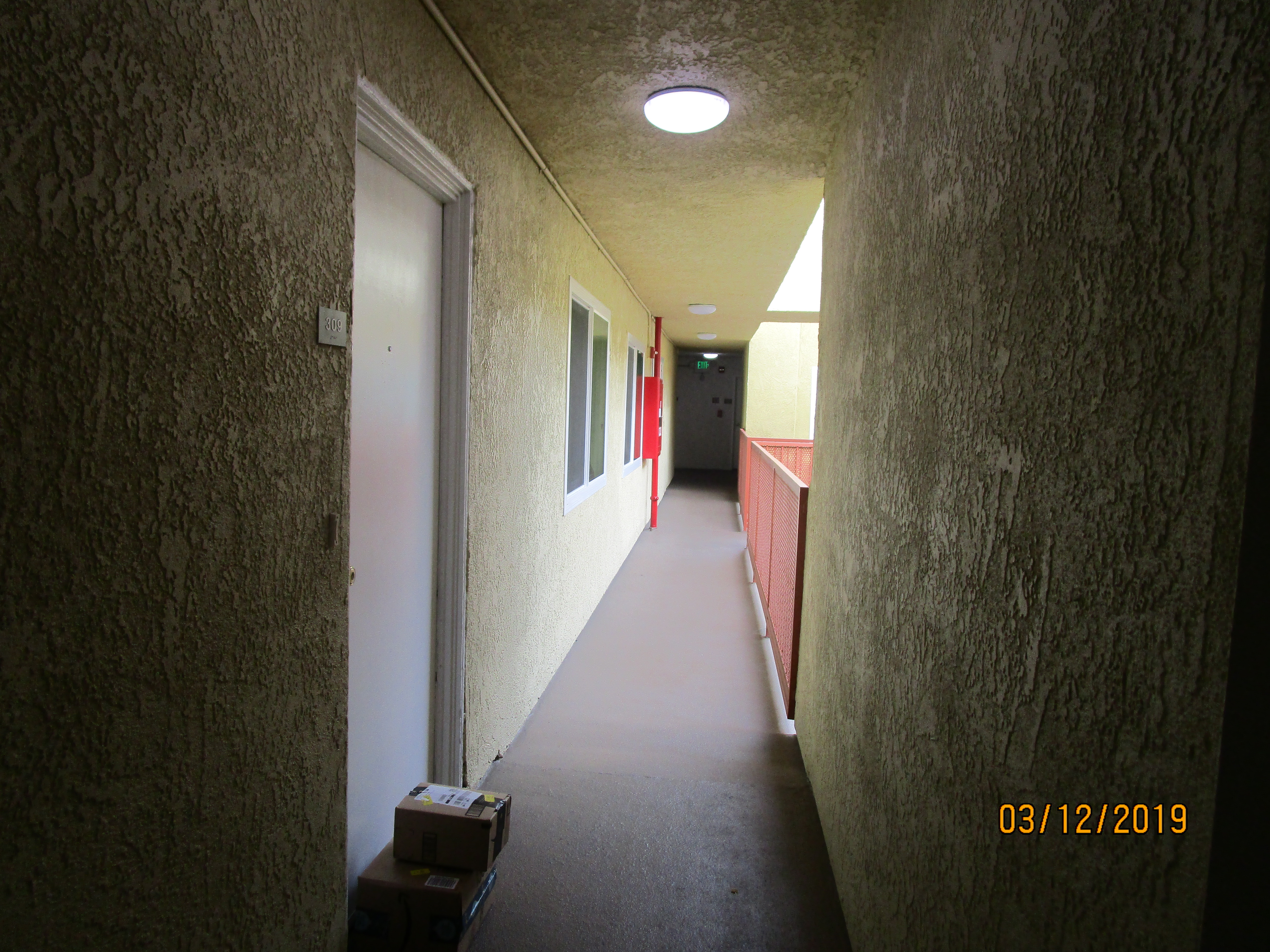 Front view of an outside hall, packages in front of a unit door.