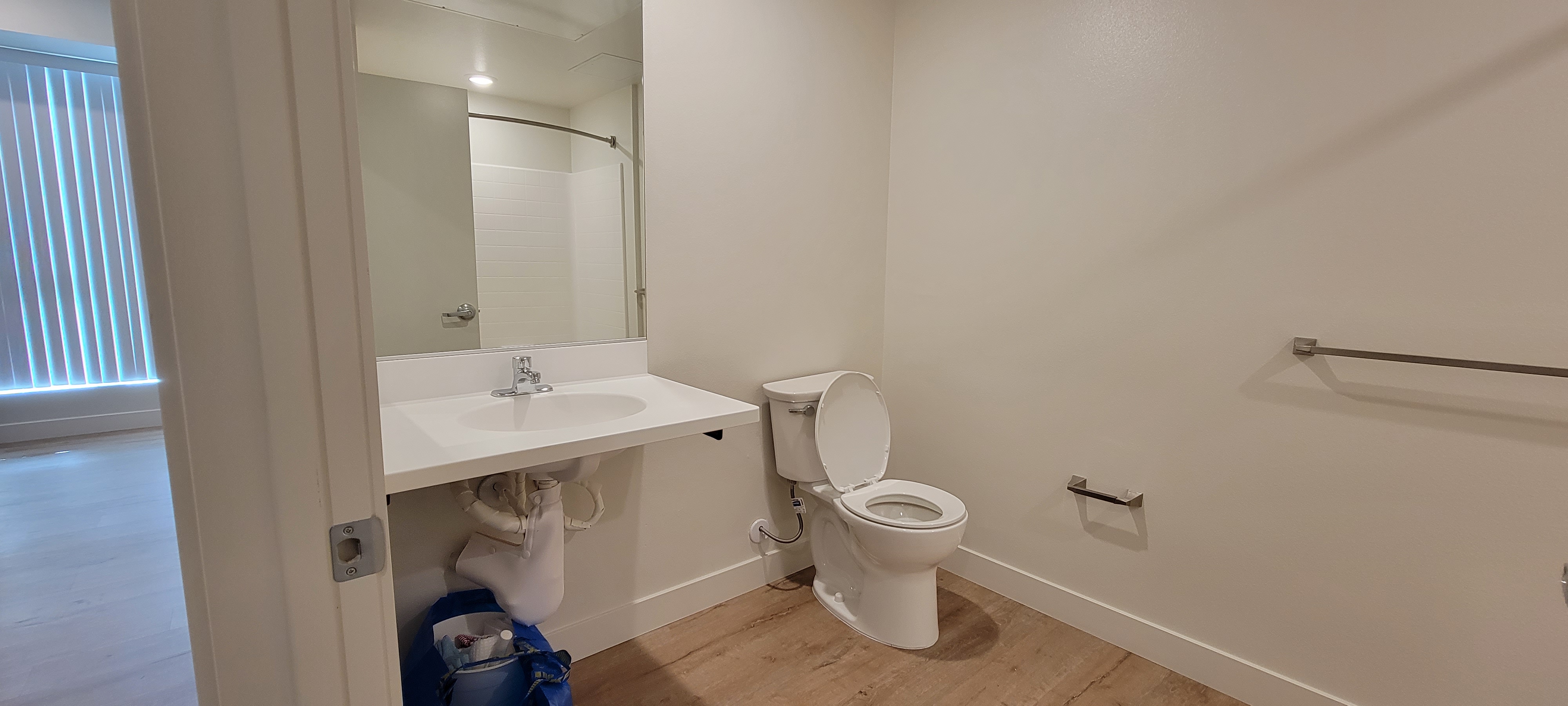 Inside view of the bathroom with toilet, wheelchair accessible sink, and mirror.