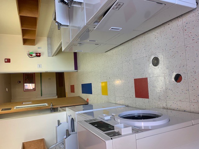 Laundry room consisting of two top-loading washers, one front-loading washer, three dryers, a folding counter, and cubbies mounted along the wall.  All machines are quarter operated.