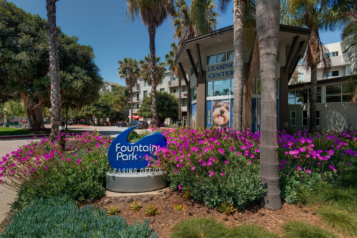 Exterior view of the Fountain Park Apartments leasing office, colorful lanscaping with palm trees