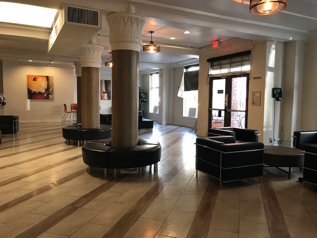 Russ Hotel lobby area. Large room with several seating areas throughout. decroative photos along wall. large glass double doors.