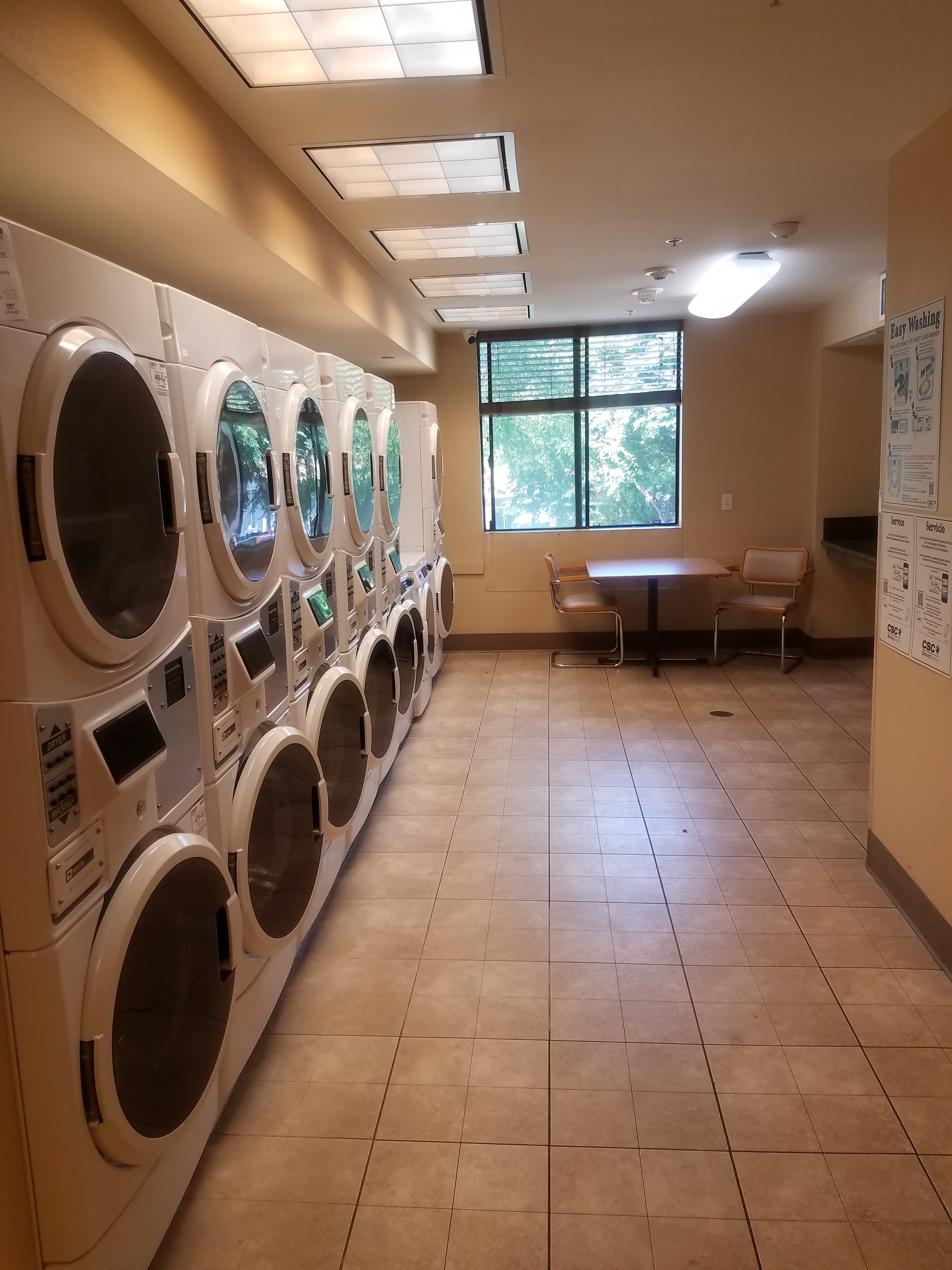 rittenhouse community laundry room. Several stacked washers and dryers. folding table and seating available.