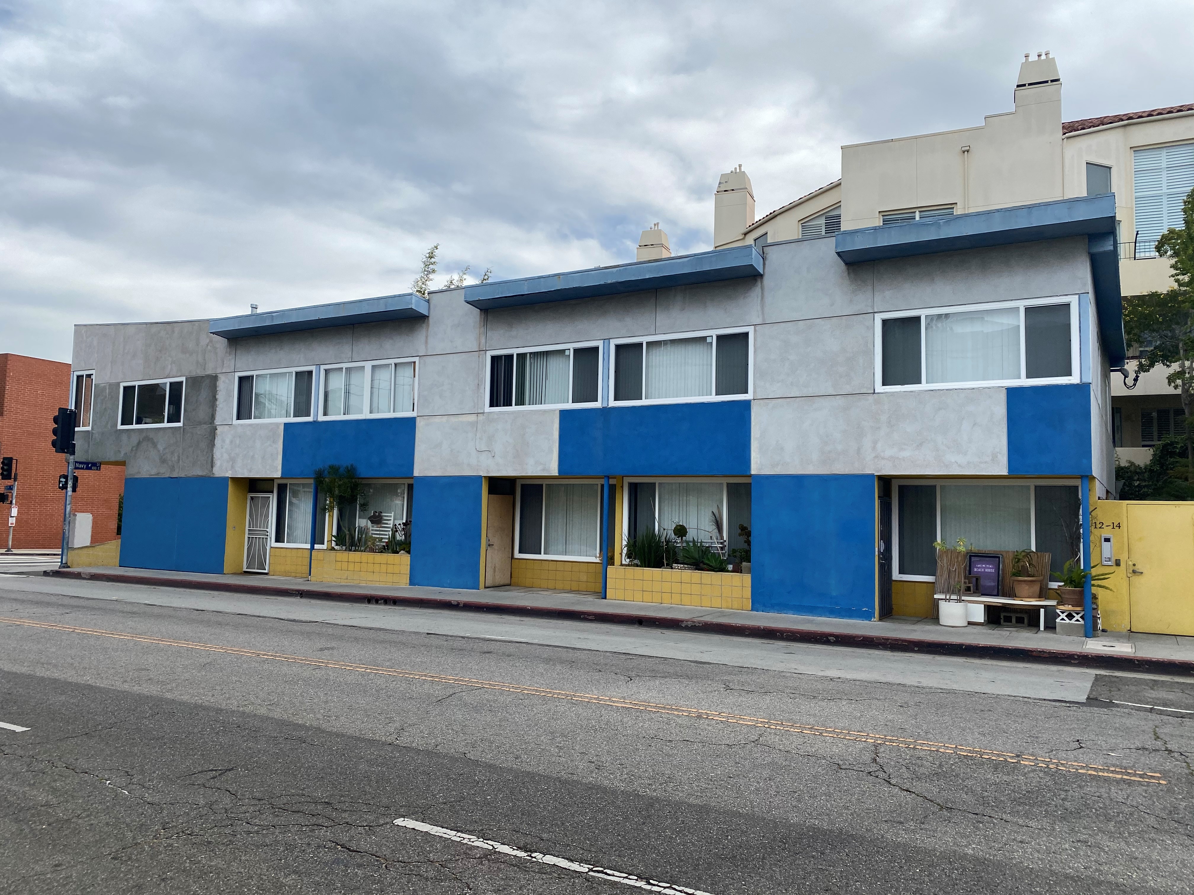 Street view of Navy Street apartments. building located on street corner. Blue and grey building with accents of yellow.