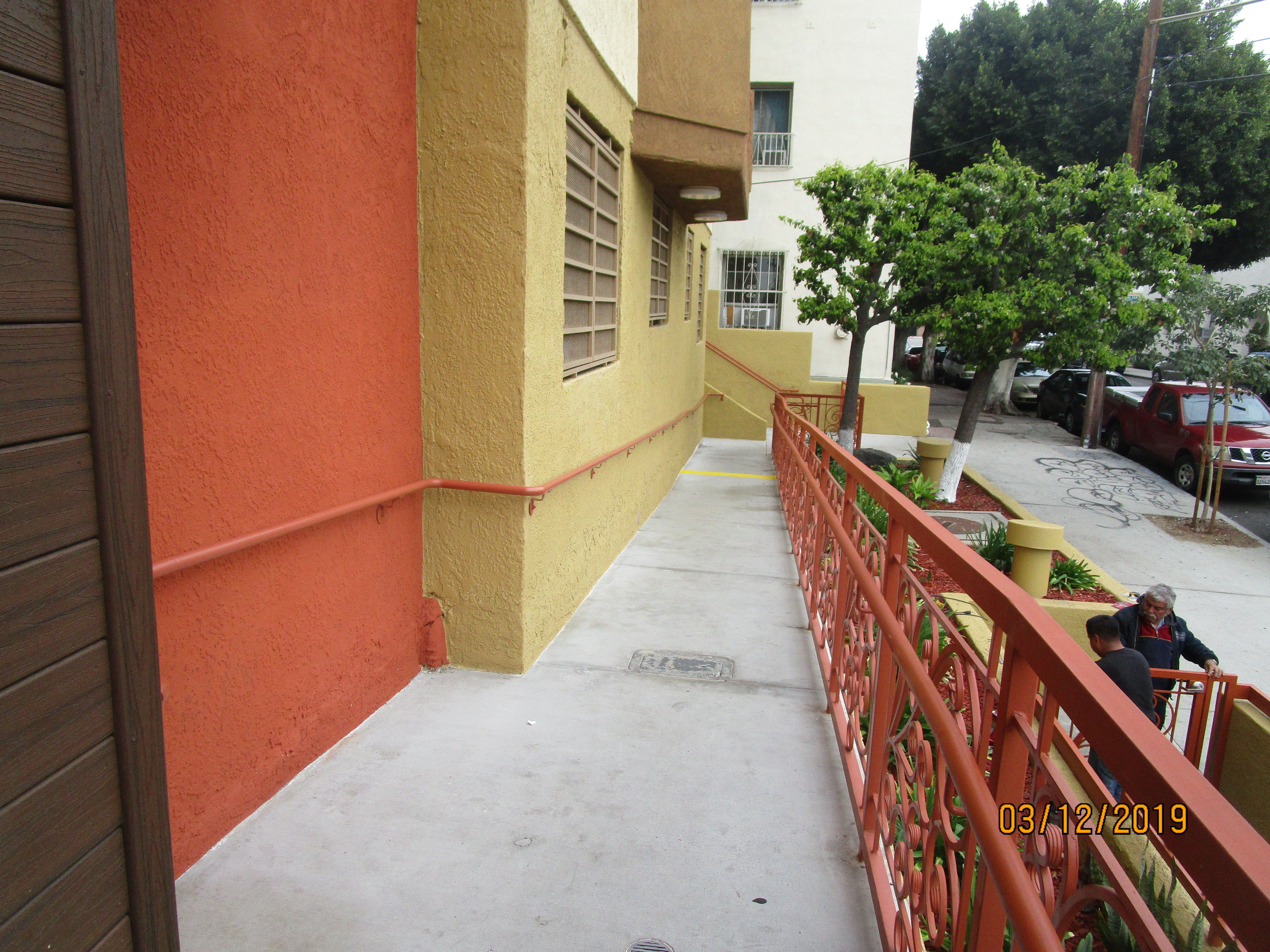 Front view of a concrete ramp, orange metal handrails on both sides.