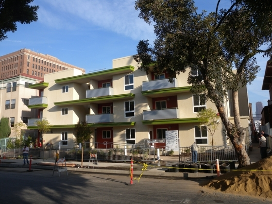 Street view of a two story building with balconies in green and white color