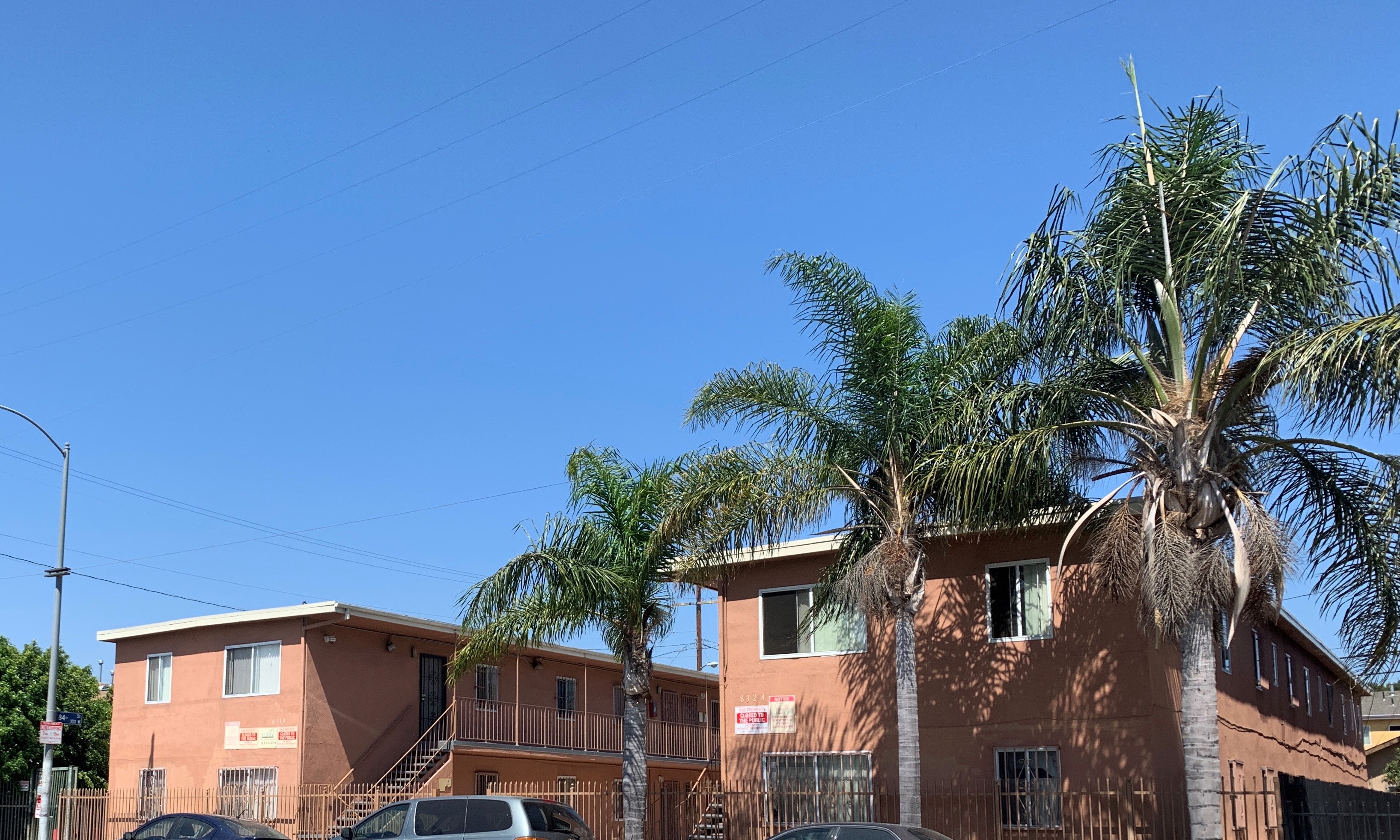 Leeward A&B exterior front view. Double story building. staris leading up to second floor. Tall full trees on street side. Cars parked on street