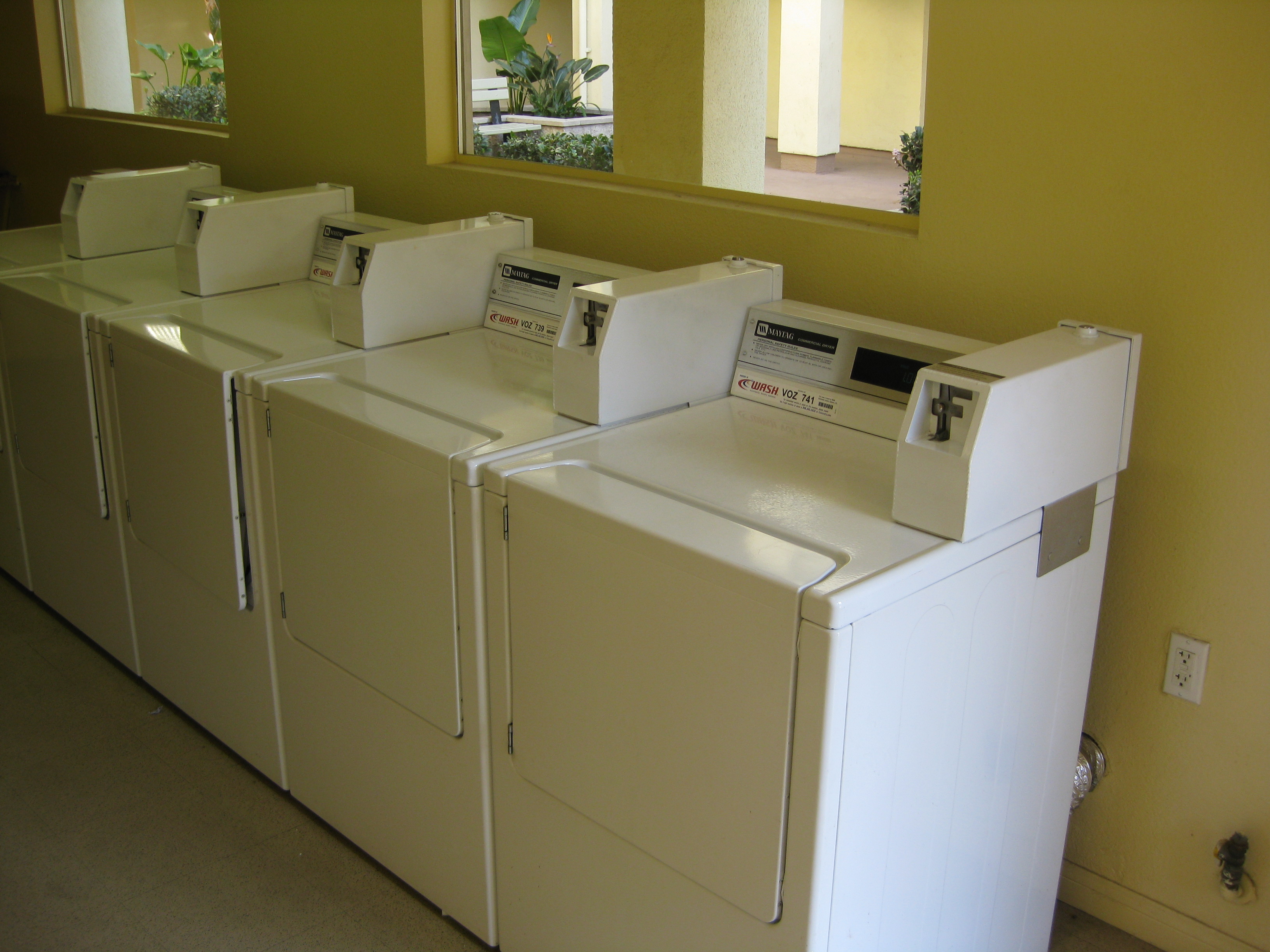 Paradise arms laundry room. four laundry machines along wall. large windows that bring in a lot of light
