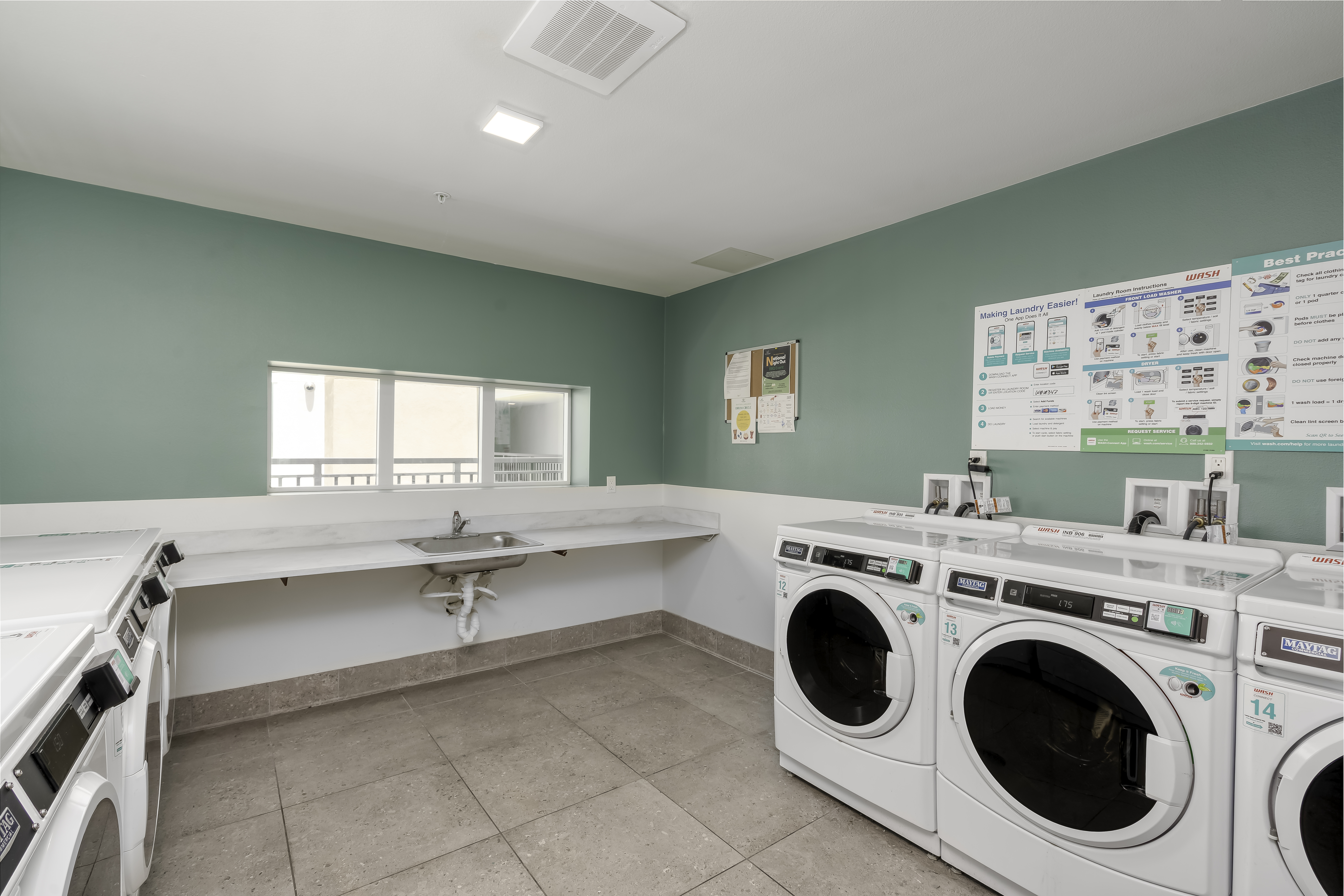 Laundry Room / Back of Property-Garden Area. Contains a few washer and dryer units with a long counter and a sink. 