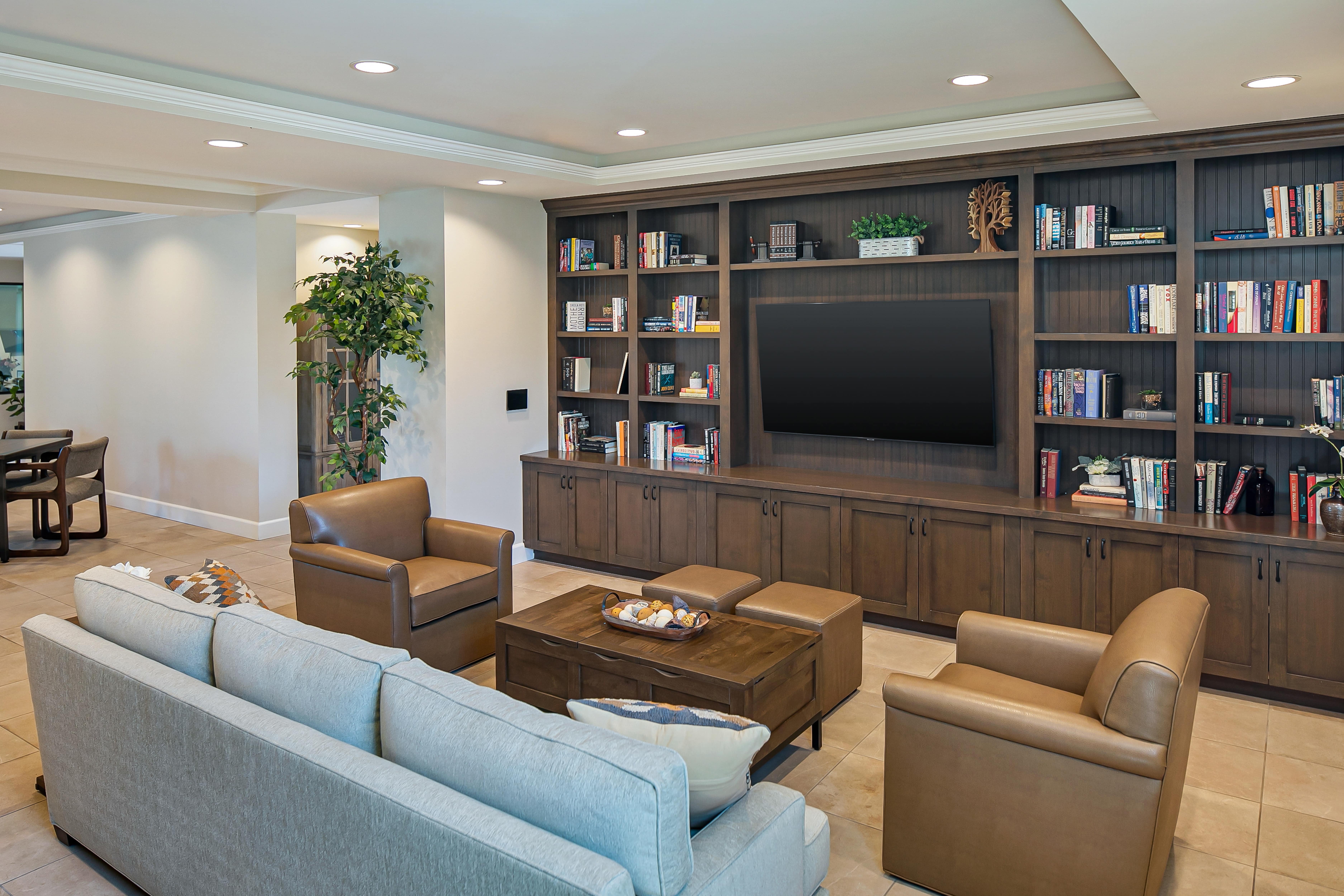 Large flat screen TV in entertainment center with couch and two leather armchairs
