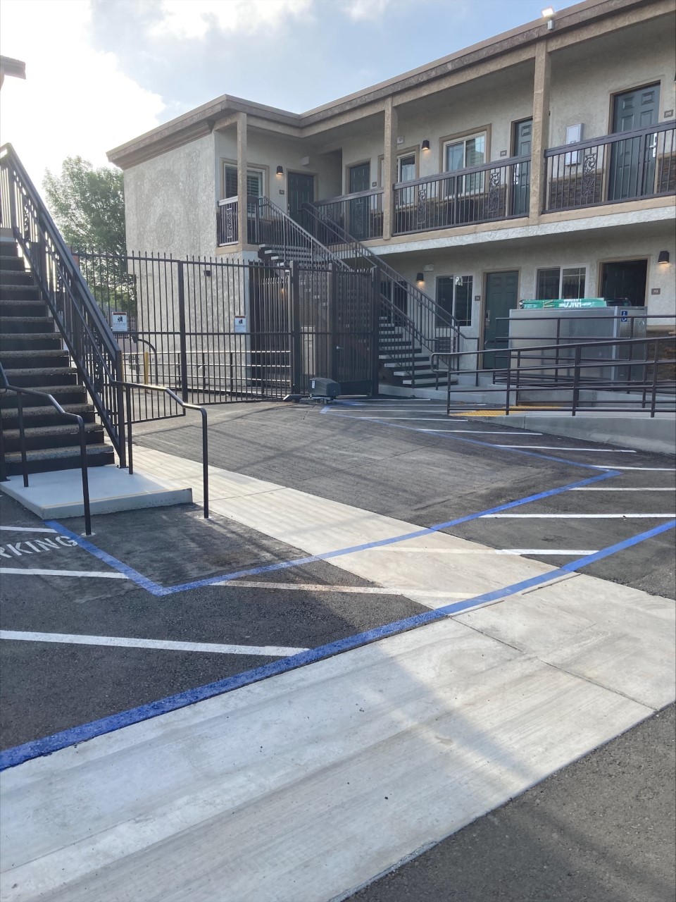 View of Western Avenue Apartments from inside the complex. There is a entry gate and gated door to get into the complex, and a wheelchair ramp to get to first floor of one of the buildings.