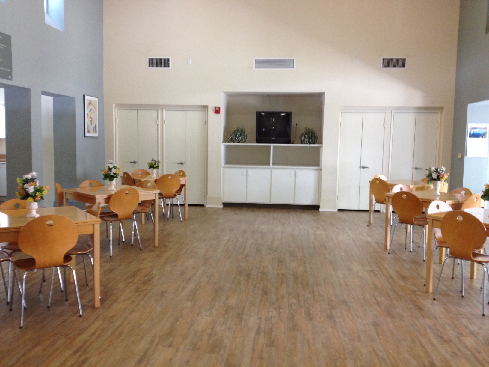 Interior view of the community room at Echo Park Senior Housing with square tables and chairs