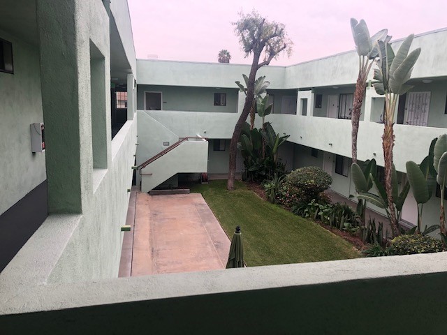 Left side view of a courtyard patio from second floor, grass bushes and plants.