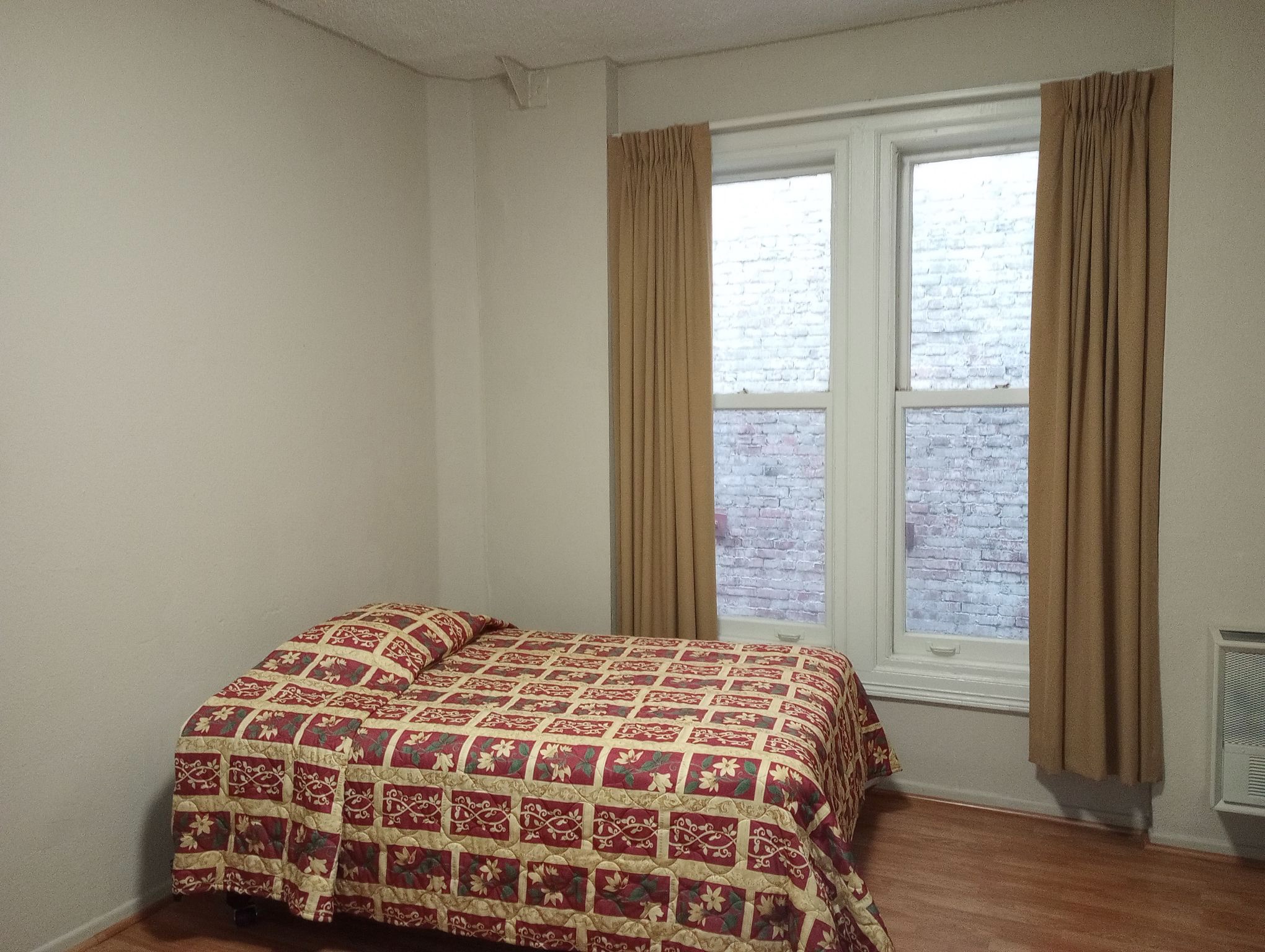 Photo of room with white walls and a bed.