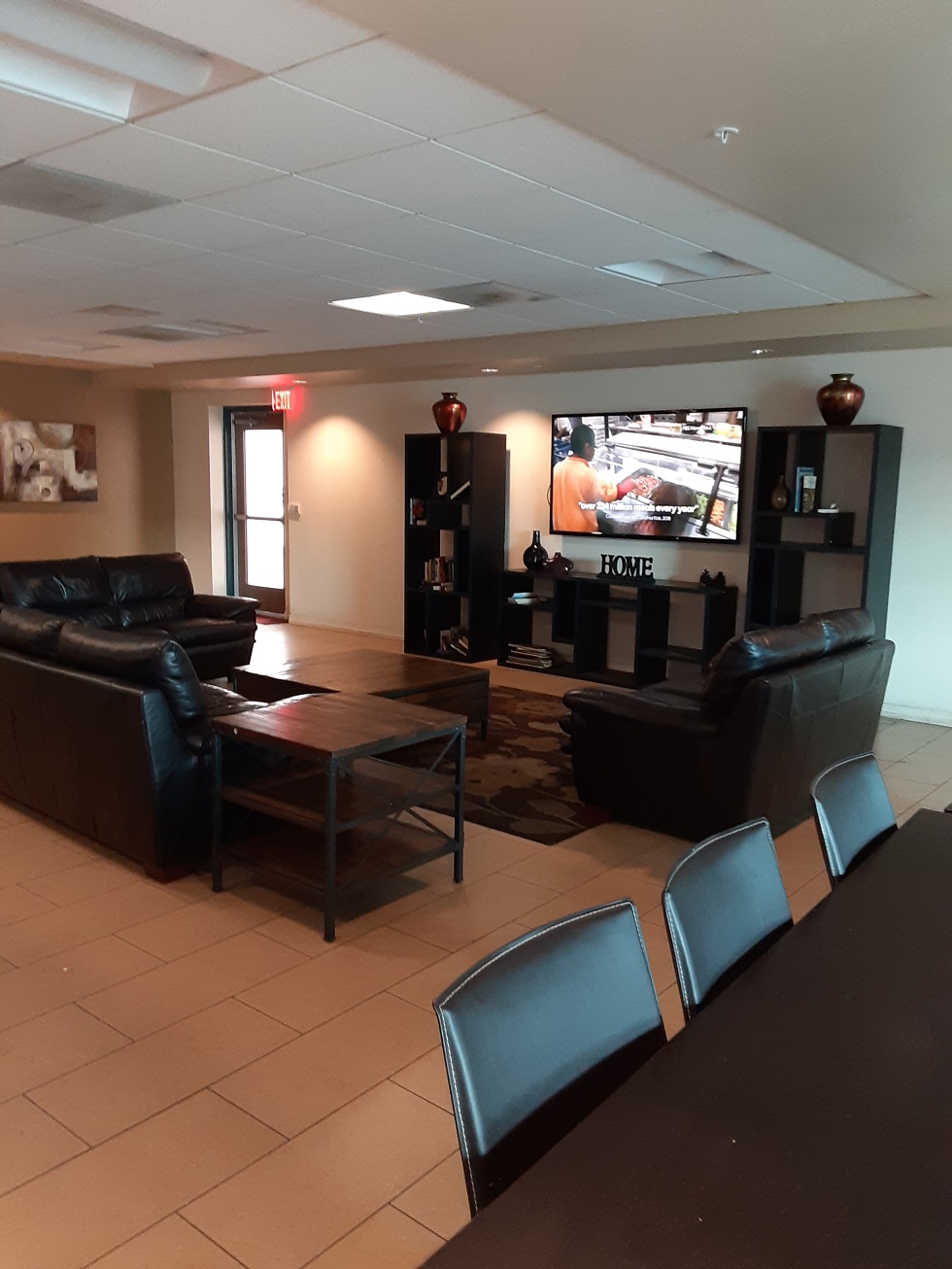 image of gateways common area. three sofas in front of tv that is mounted on wall. large entertainment center.