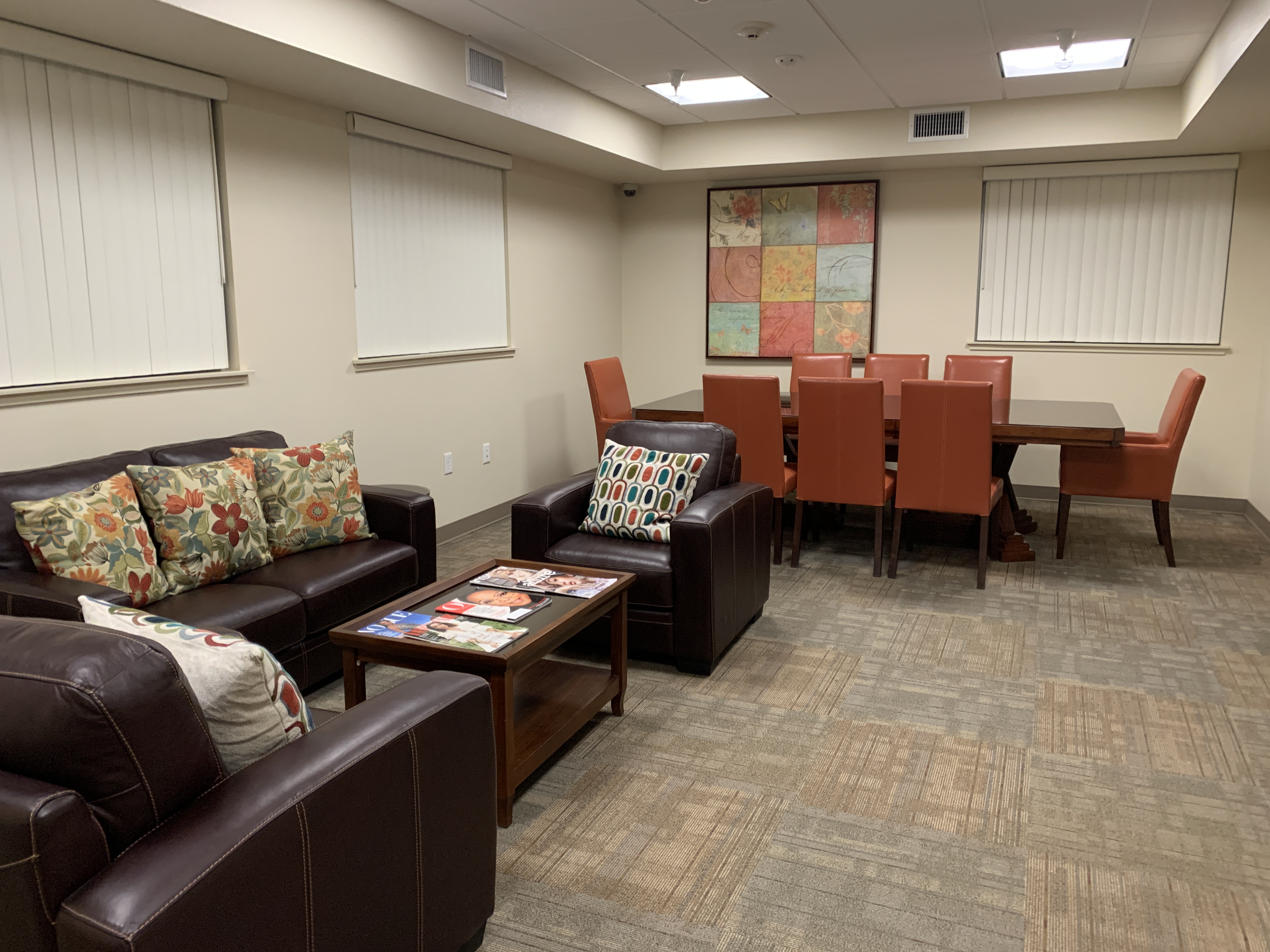 Conference room with a couch, two sofa chairs, a coffee table, and a conference table.