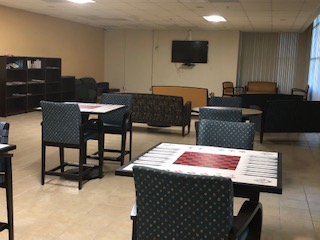 Interior viewo of a community room at Vermont Seniors. Square tables and chairs with a checker board painted on each table