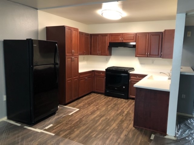 View of kitchen. Upper and lower cabinets, range stove, and fridge